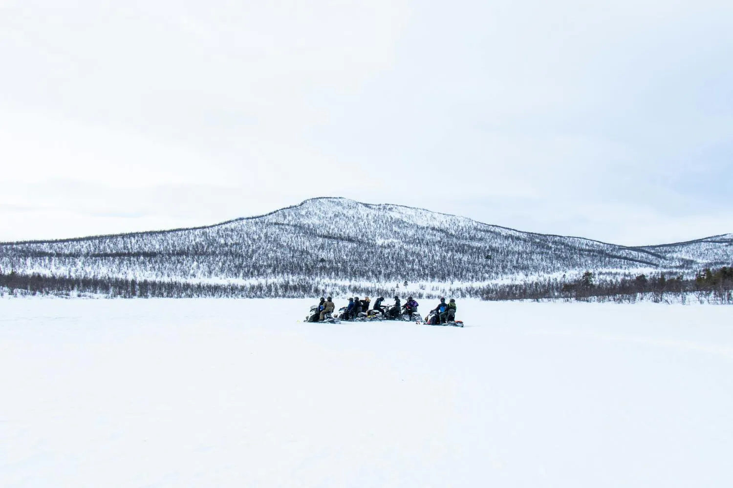 Snowy day with people riding the snowmobiles in the distance