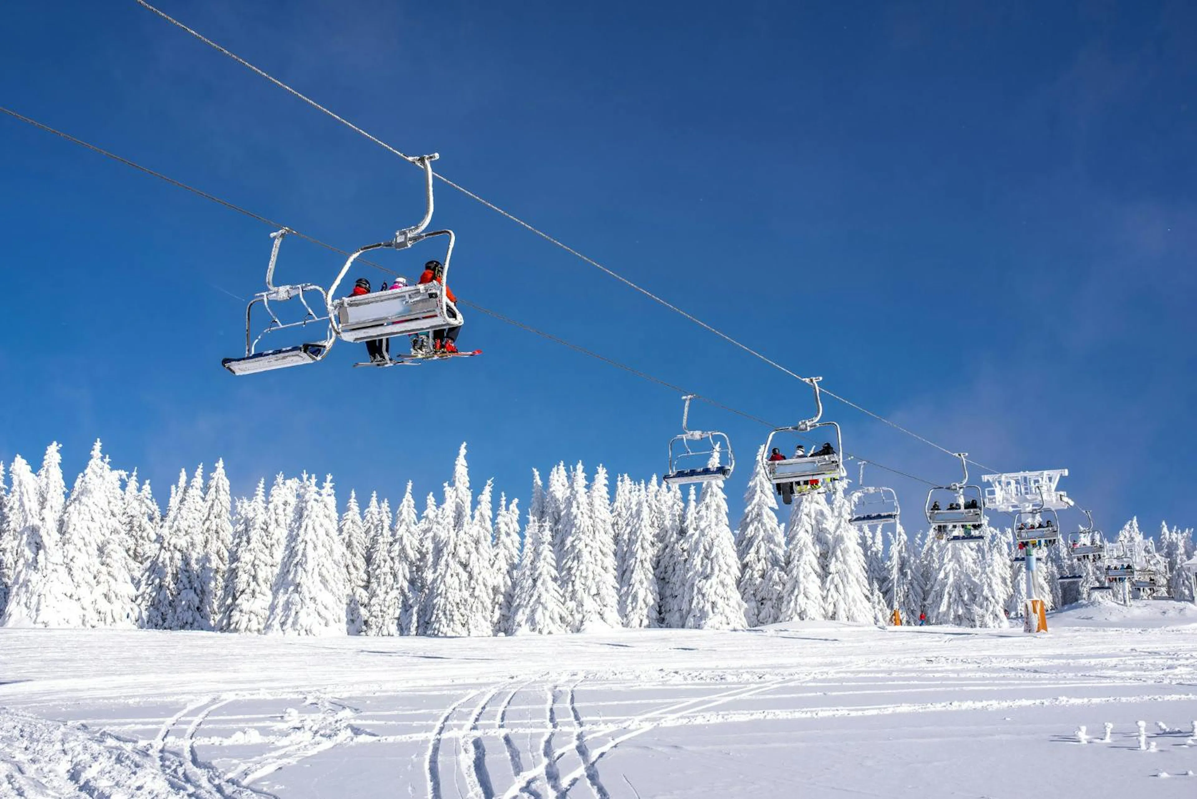 Skiers on a ski lift at a mountain resort with the sky and mountains