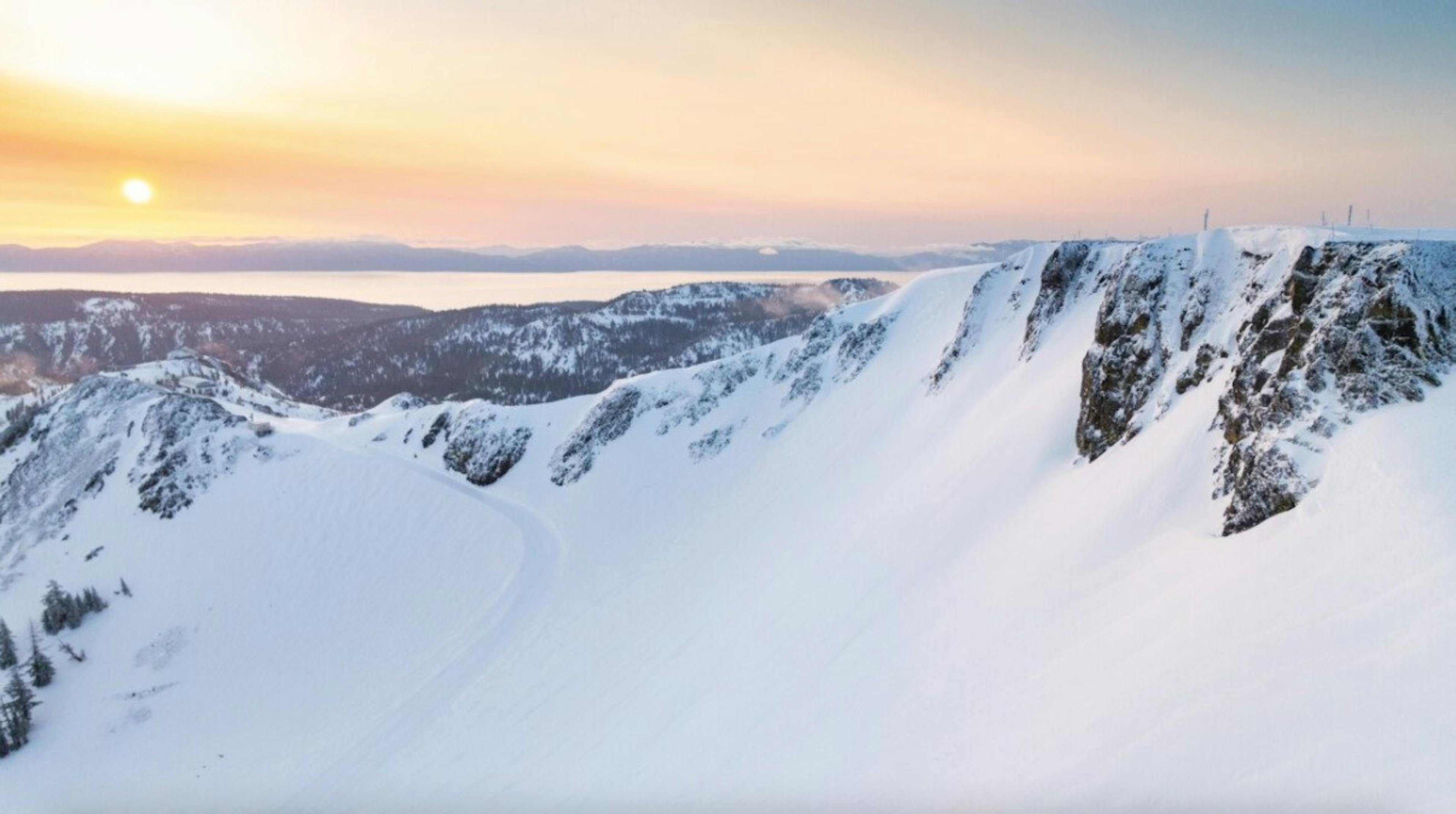 Aerial shot of fresh snow over the Tahoe Basin and Sierra Nevada mountain range while the sun sets