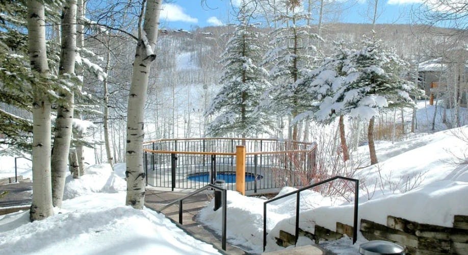 Outdoor hot tub at Woodrun V Snowmass surrounded by snow on a beautiful bluebird day
