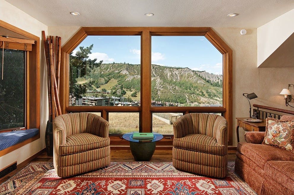 A huge window with a beautiful view of the Aspen Snowmass slopes framed by two armchairs in Residence 5 at Woodrun V Lodge