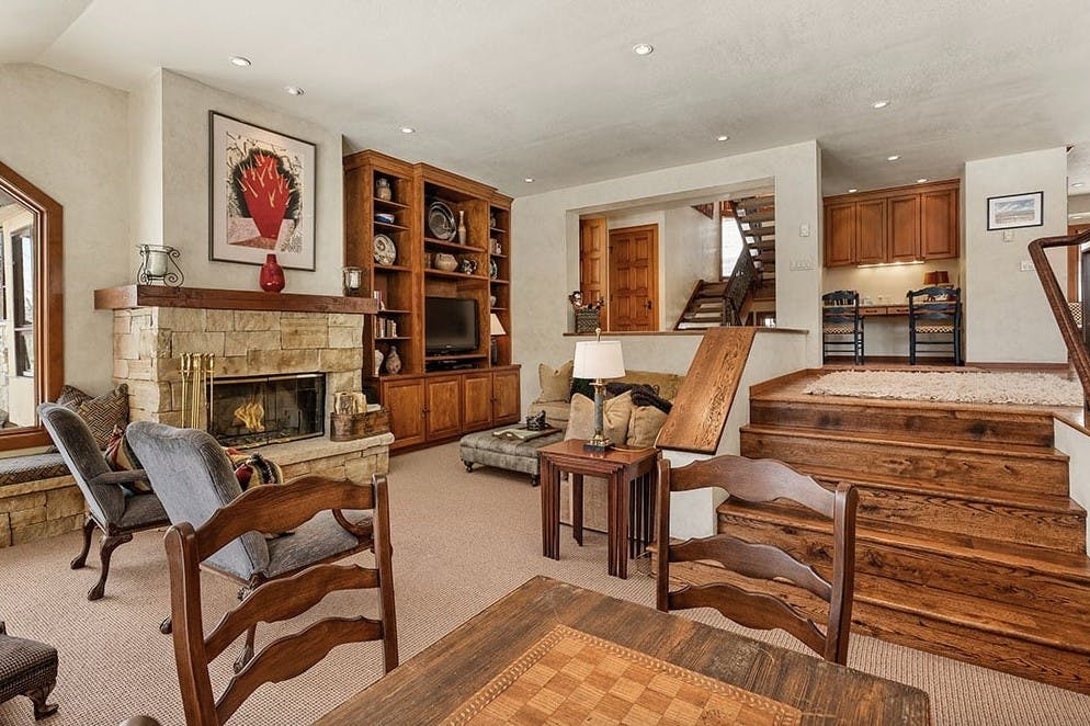 Living room with wooden chairs, a couch, dining room table, and a roaring fireplace in Residence 5 at Woodrun V Snowmass