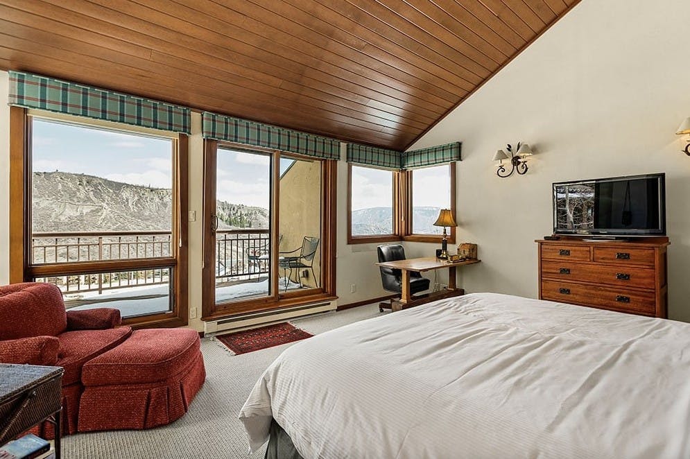 Bedroom inside Residence 5 at Woodrun V Snowmass with huge windows, alpine views, an outdoor patio, rustic cabin feel, and cozy bed