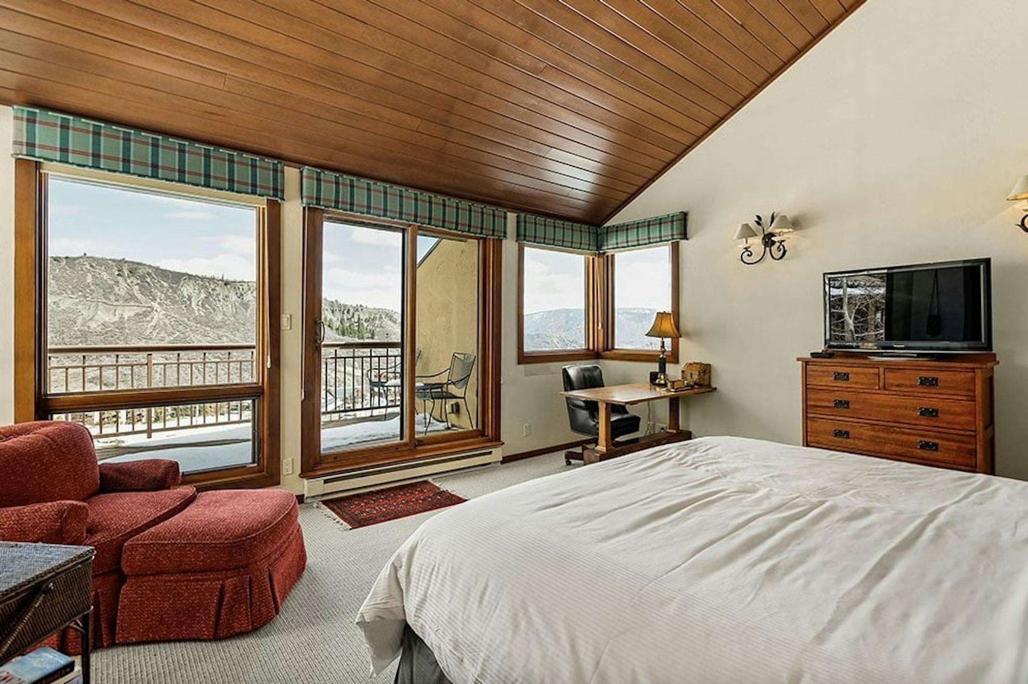Bedroom inside Residence 5 at Woodrun V Snowmass with huge windows, alpine views, an outdoor patio, rustic cabin feel, and cozy bed 