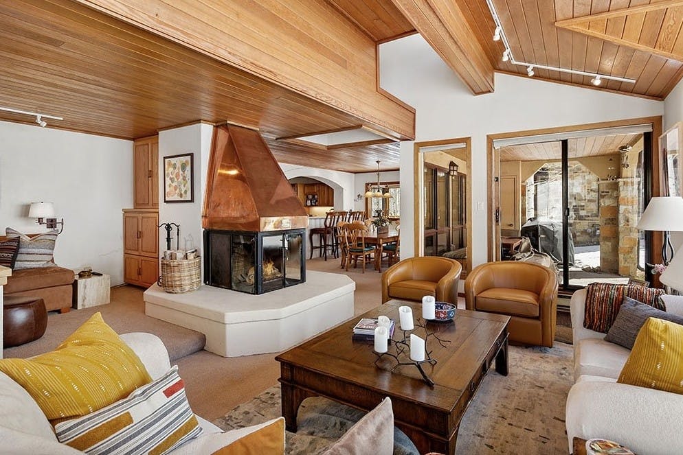 Cozy living room with roaring fireplace, cozy couches, two armchairs, and an outdoor patio in Residence 17 at Woodrun V Snowmass