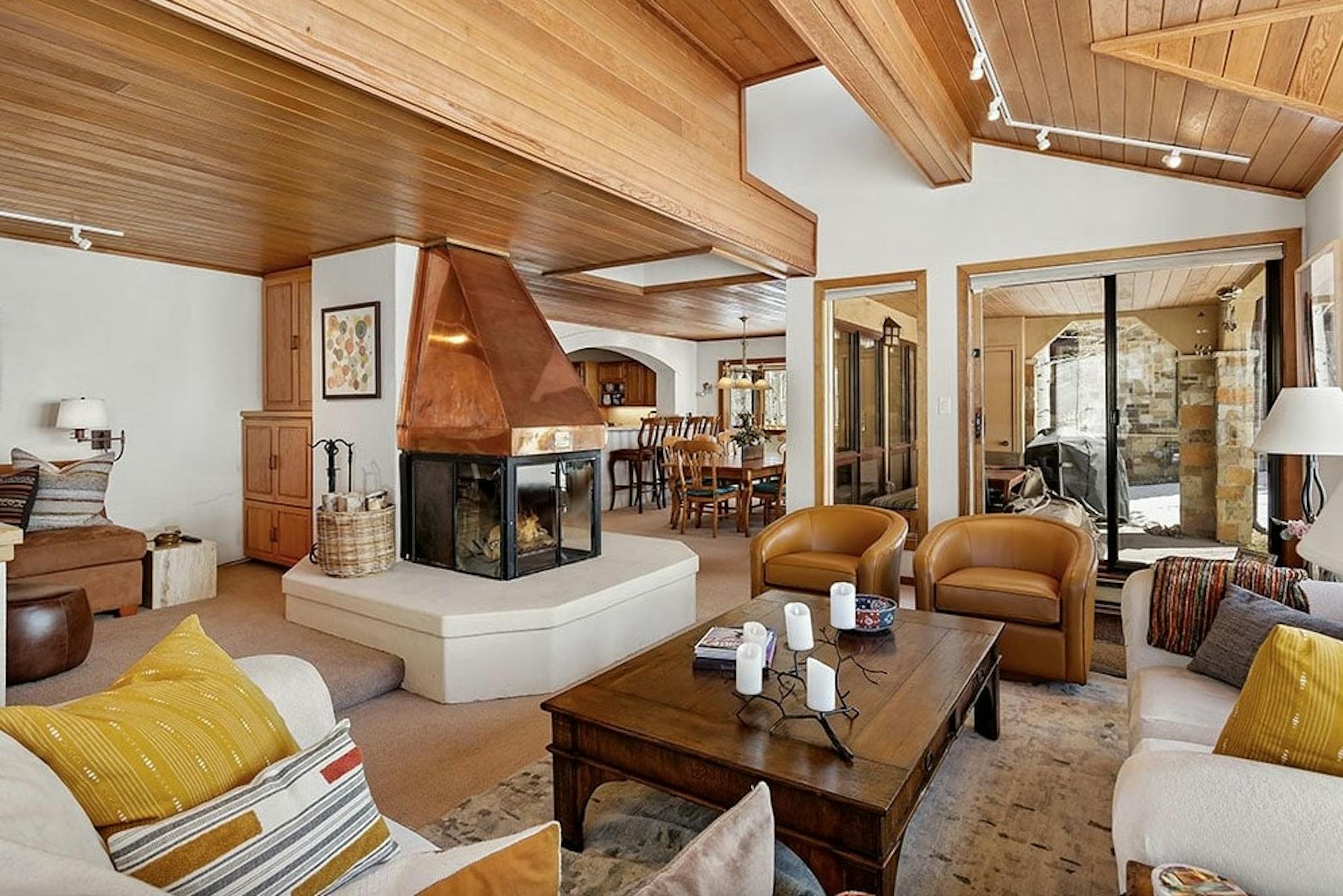 Cozy living room with roaring fireplace, cozy couches, two armchairs, and an outdoor patio in Residence 17 at Woodrun V Snowmass