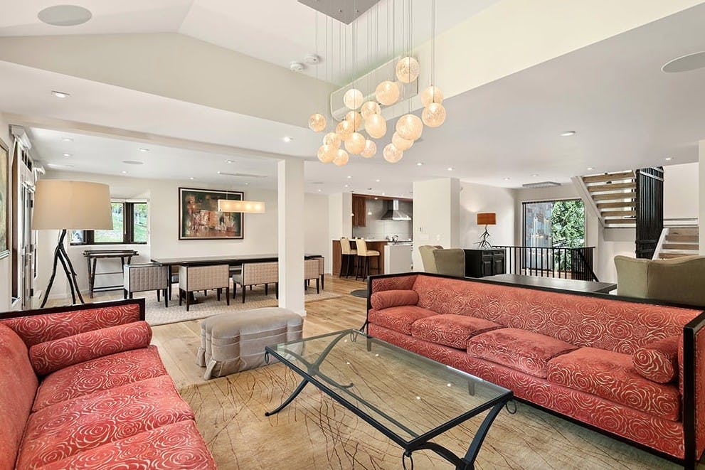 The sleek living room of Residence 16 at Woodrun V Snowmass with red lacy couches, modern lighting, and forest views
