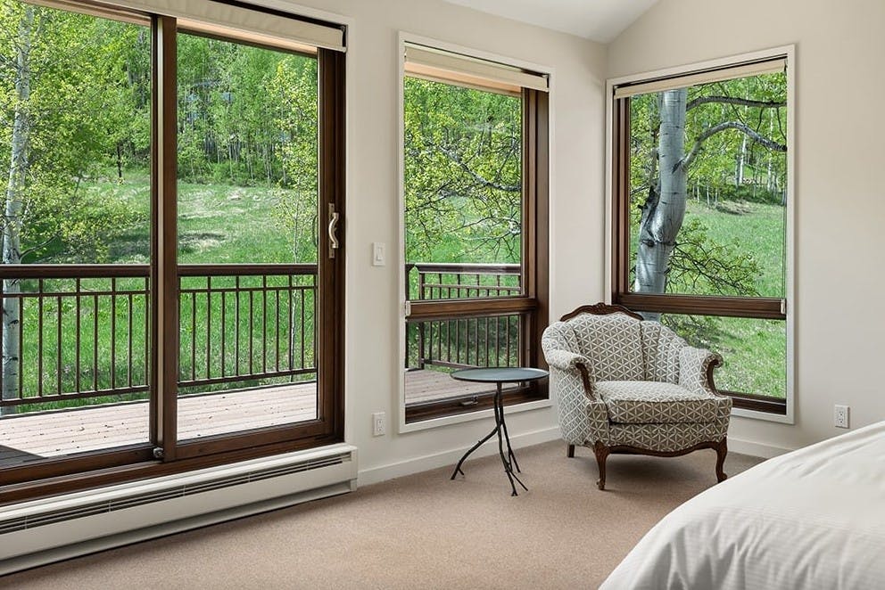 Hude bedroom windows looking out to beautiful forest views on an outdoor patio at Residence 16 at Woodrun V Snowmass