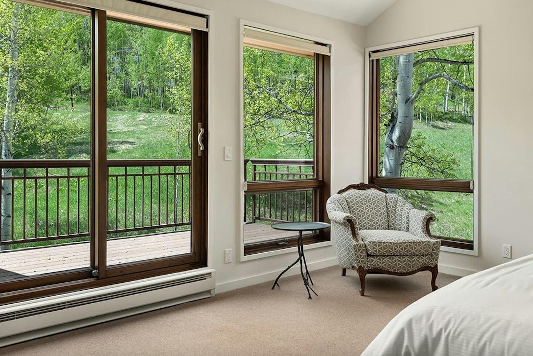 Hude bedroom windows looking out to beautiful forest views on an outdoor patio at Residence 16 at Woodrun V Snowmass