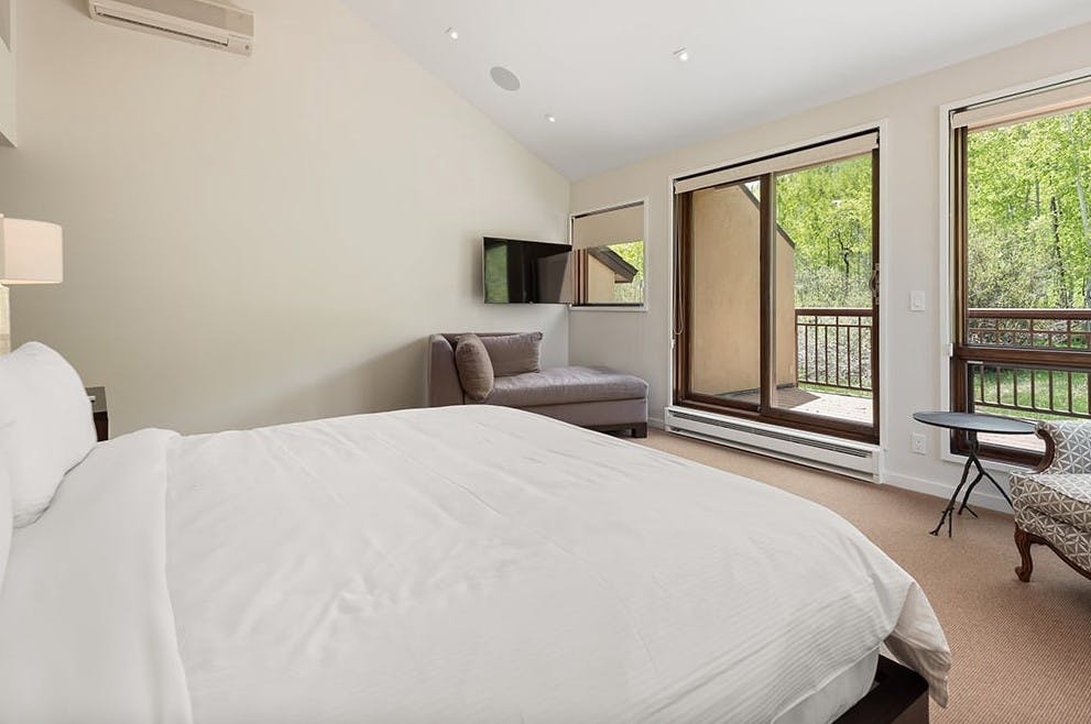 Minimal bedroom at Residence 16 at Woodrun V Snowmass with a king bed with a white comforter and an outdoor patio