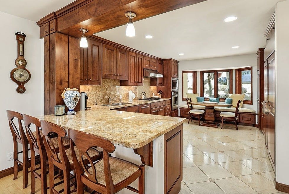 Kitchen and bar counter with rustic chairs, wooden cabinets, and pretty forest views
