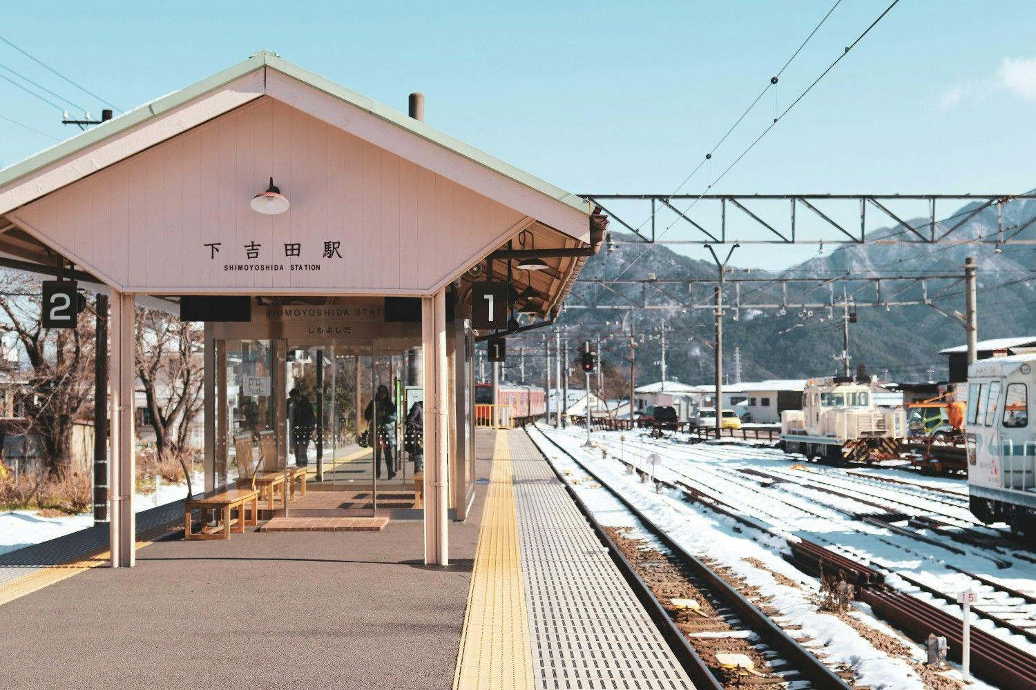 Japanese train station lightly covered in snow with alpine mountain backdrop