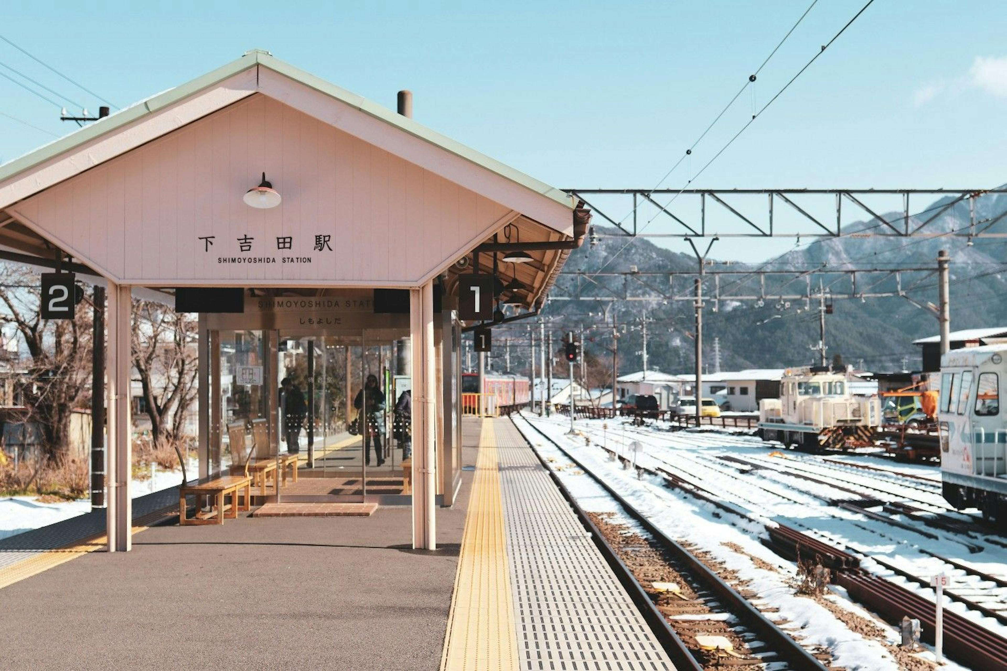 Japanese train station lightly covered in snow with alpine mountain backdrop