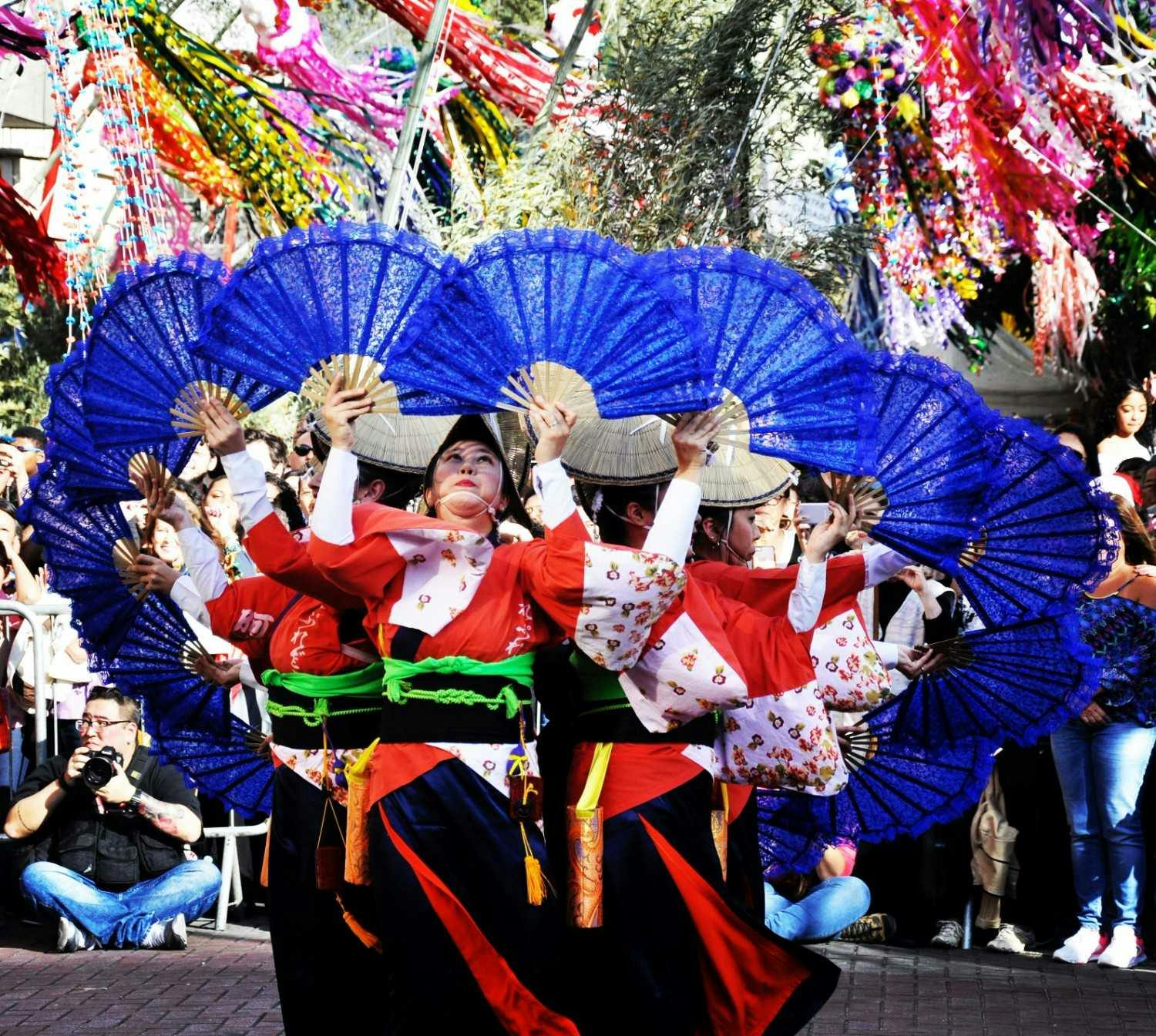 Japanese festival with colorful streamers hanging in the air, framing Japanese fan dancers wearing kimonos