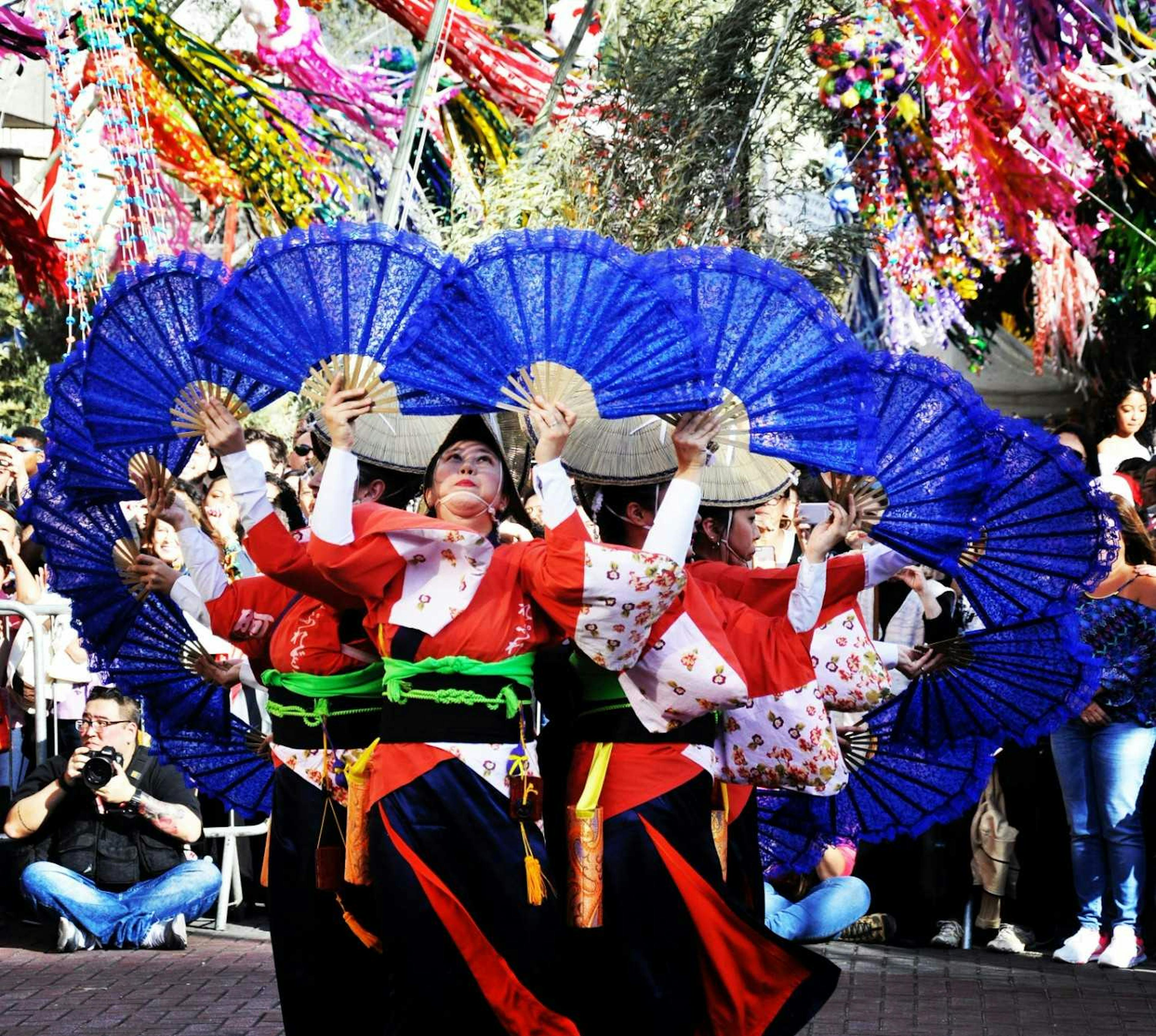 Japanese festival with colorful streamers hanging in the air, framing Japanese fan dancers wearing kimonos