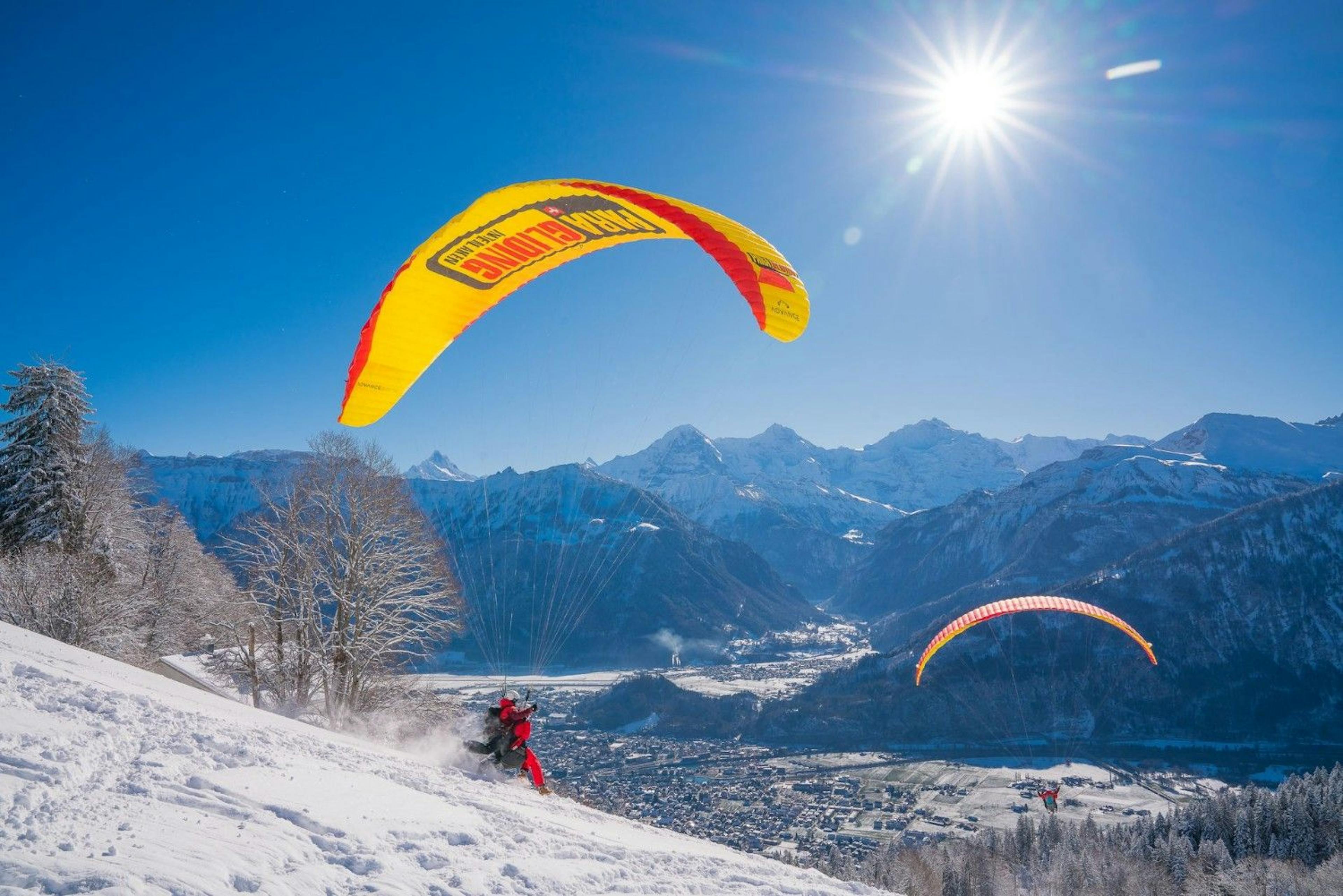 Two paragliders glide over Interlaken on a sunny winter day