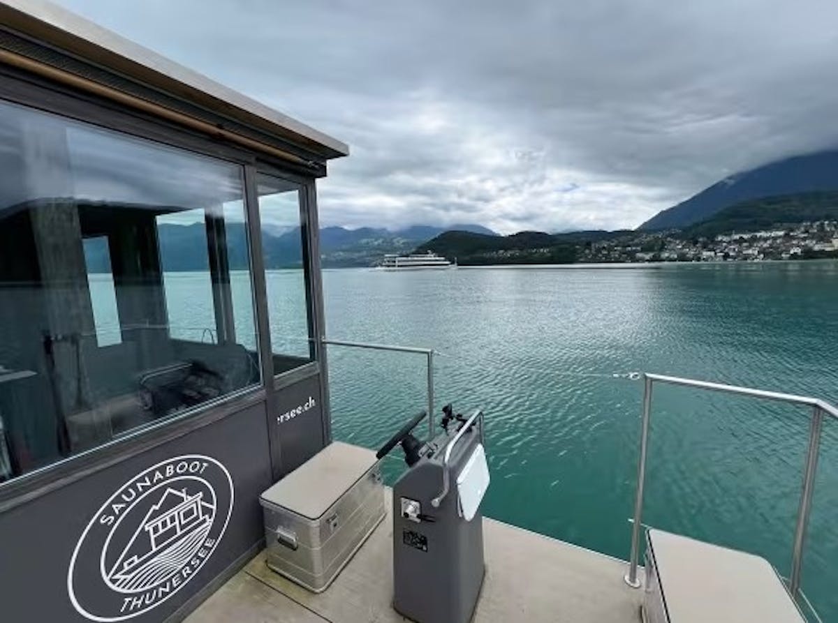 Standing on the deck of the Sauna Boat overlooking the bright blue waters of Lake Thun and alpine mountains