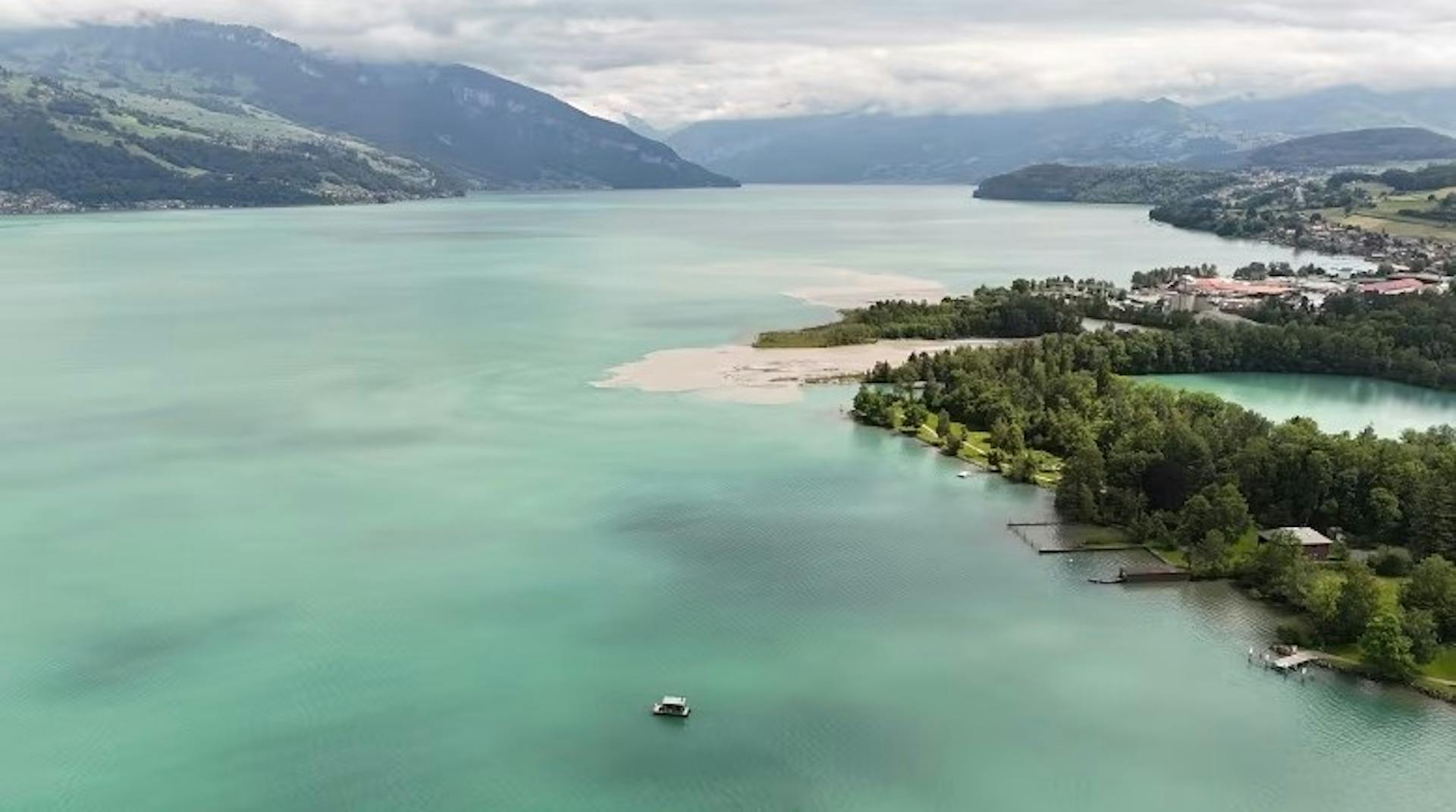 Aerial view of the Sauna Boat on the bright blue waters of Lake Thun framed by alpine mountains