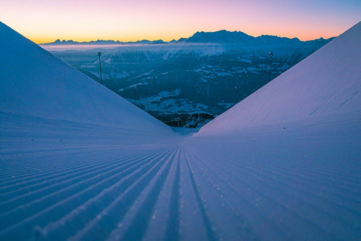 Half pipe at LAAX at sunrise framing alpine mountains and a pink sky