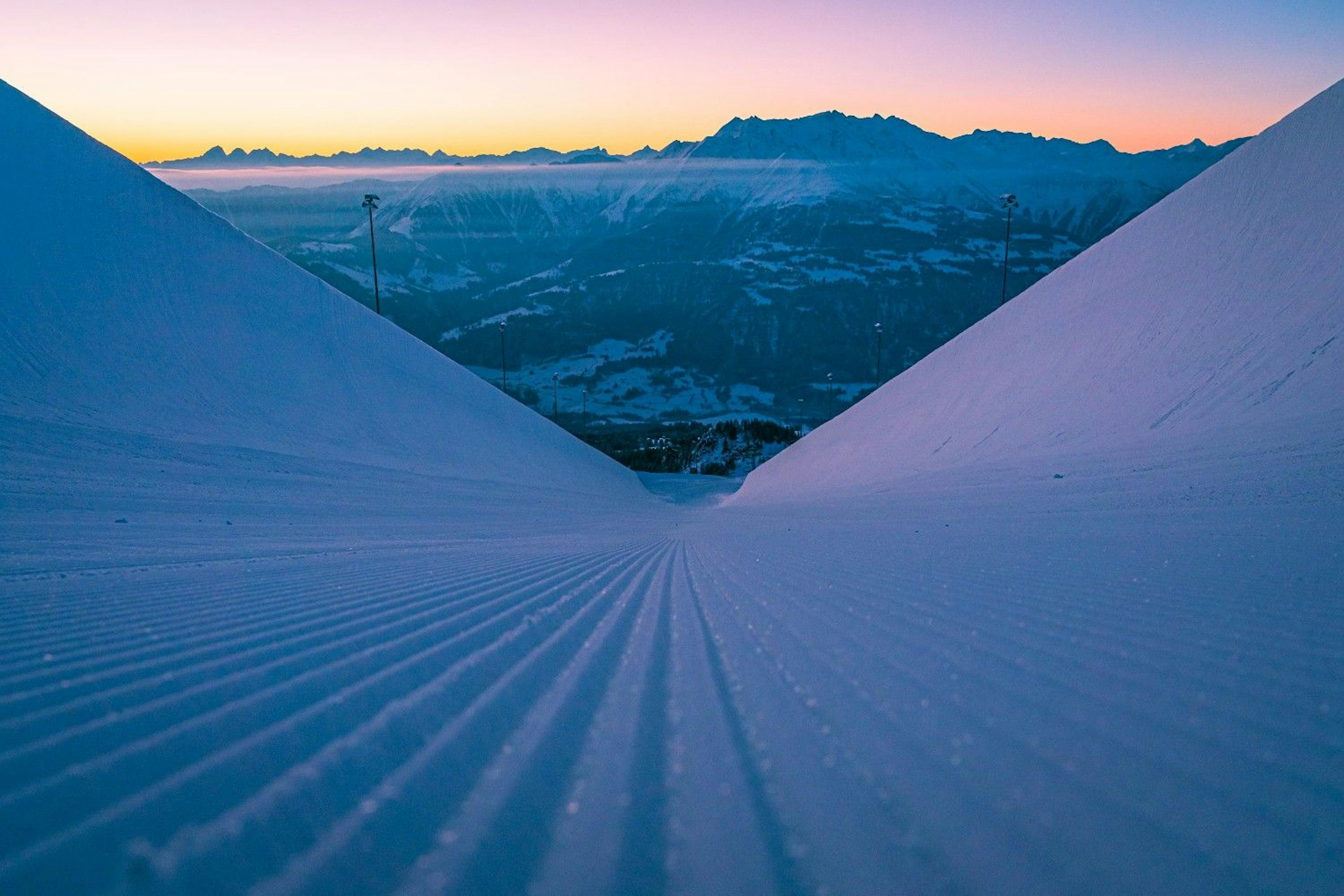 Half pipe at LAAX at sunrise framing alpine mountains and a pink sky