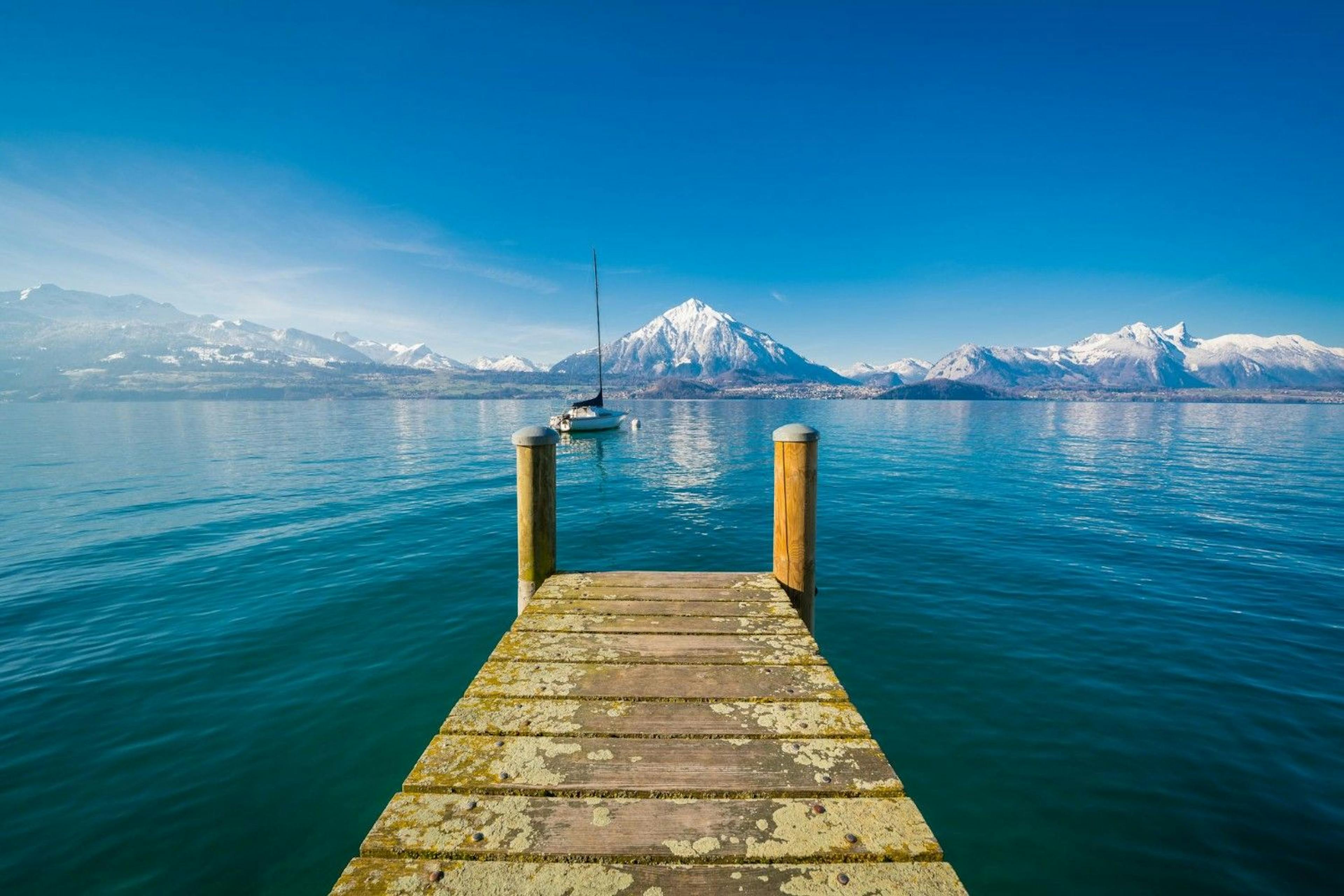 View of Lake Thun from a boat dock with snow-covered alpine mountains framing the lake