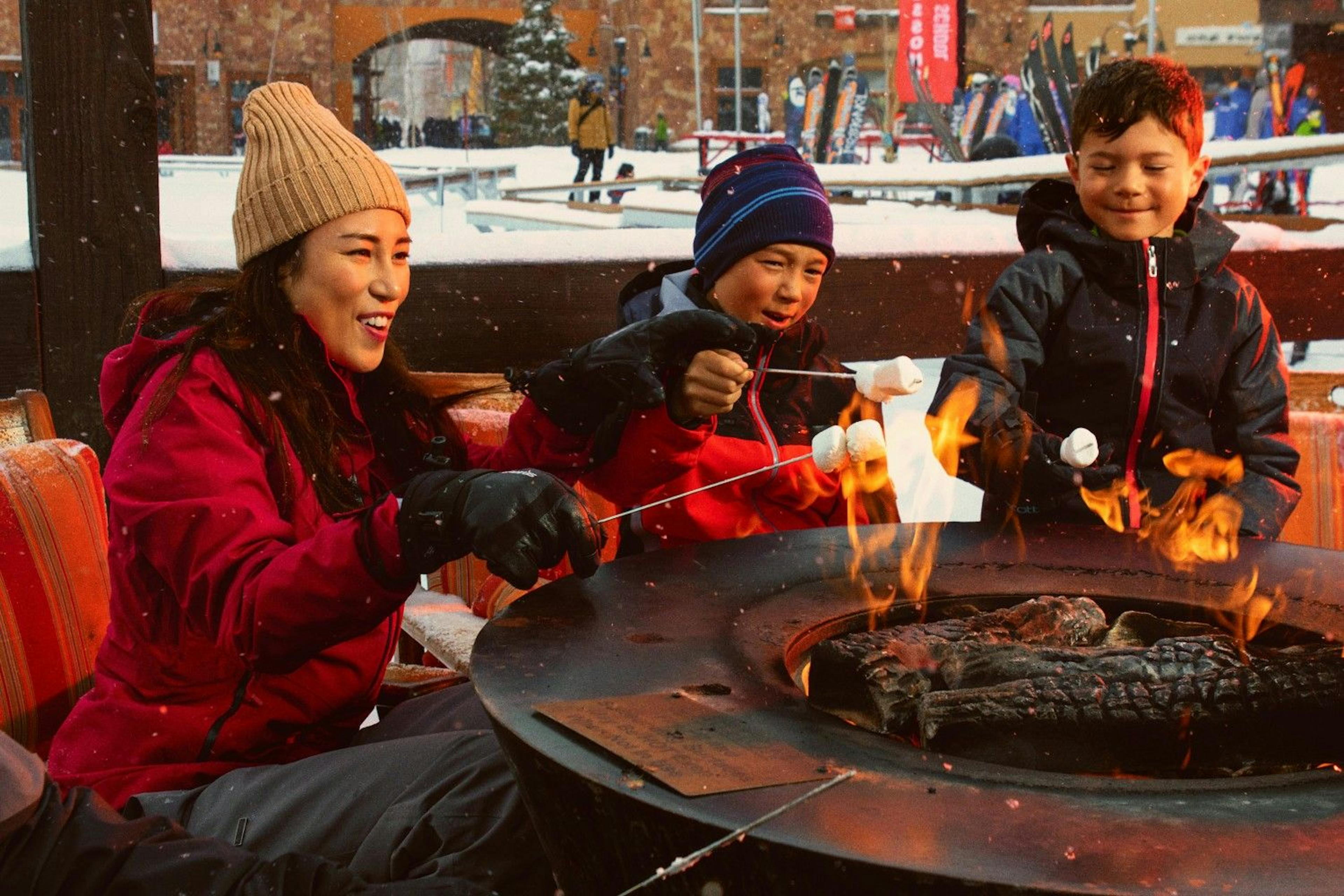 Family roasting marshmallows over the outdoor fire pit in Canyons Village at Park City