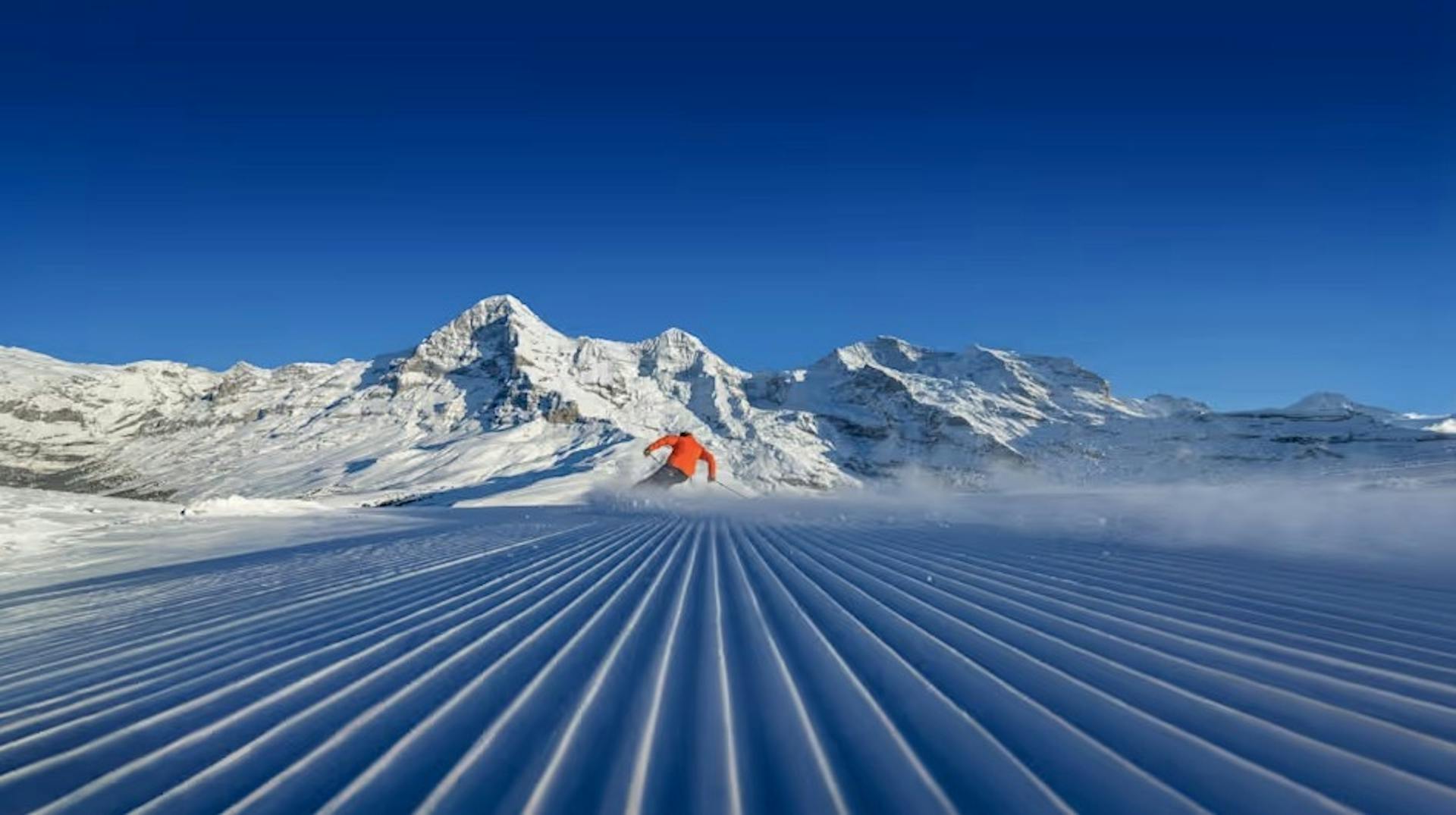 Skier on a freshly groomed slope at Grindelwald framed by the Alps on a clear day