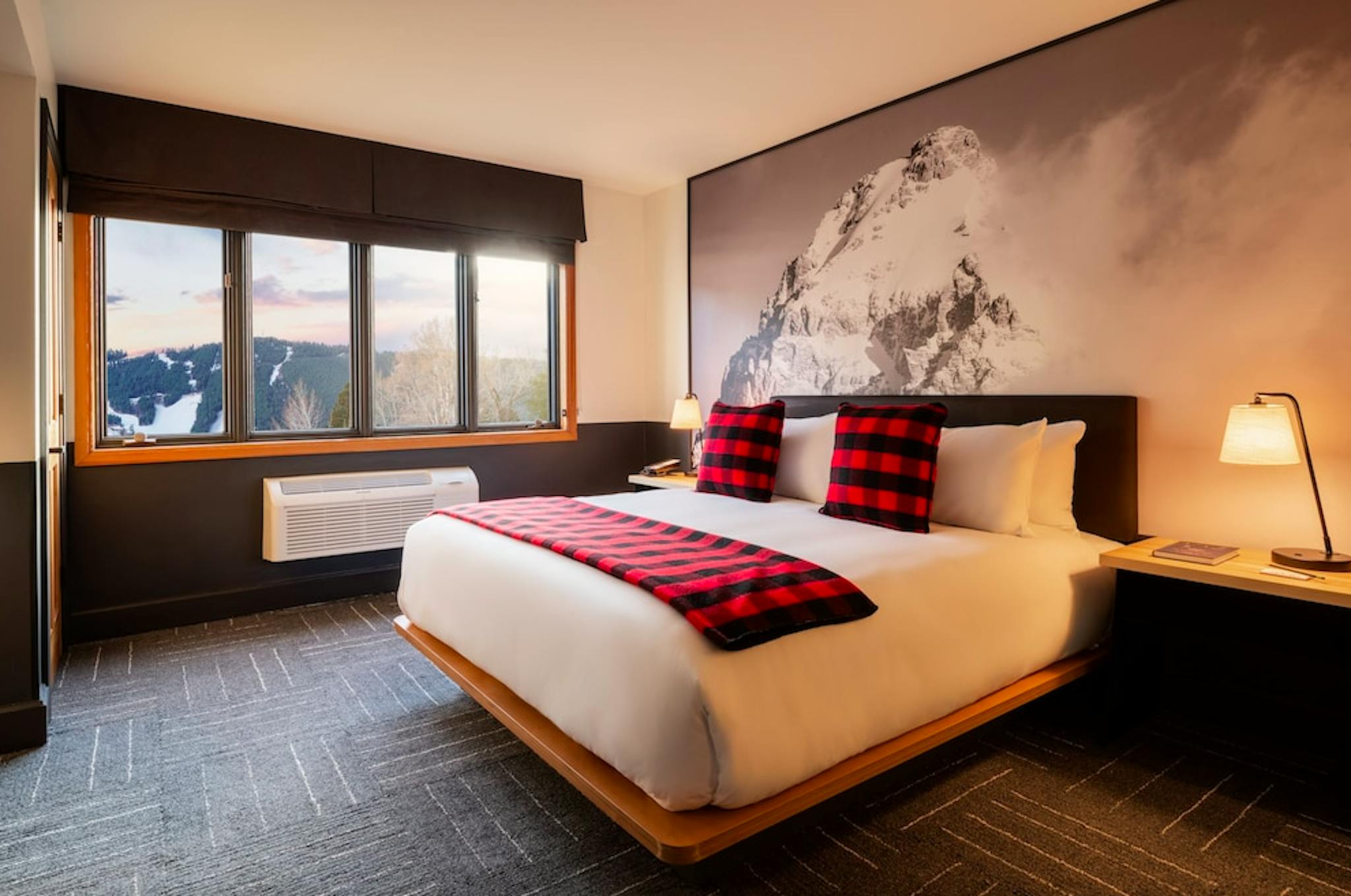 Bedroom of a hotel room at Mountain Modern Jackson with a huge king bed with a white comforter and gorgeous views of the slopes from the bedroom windows