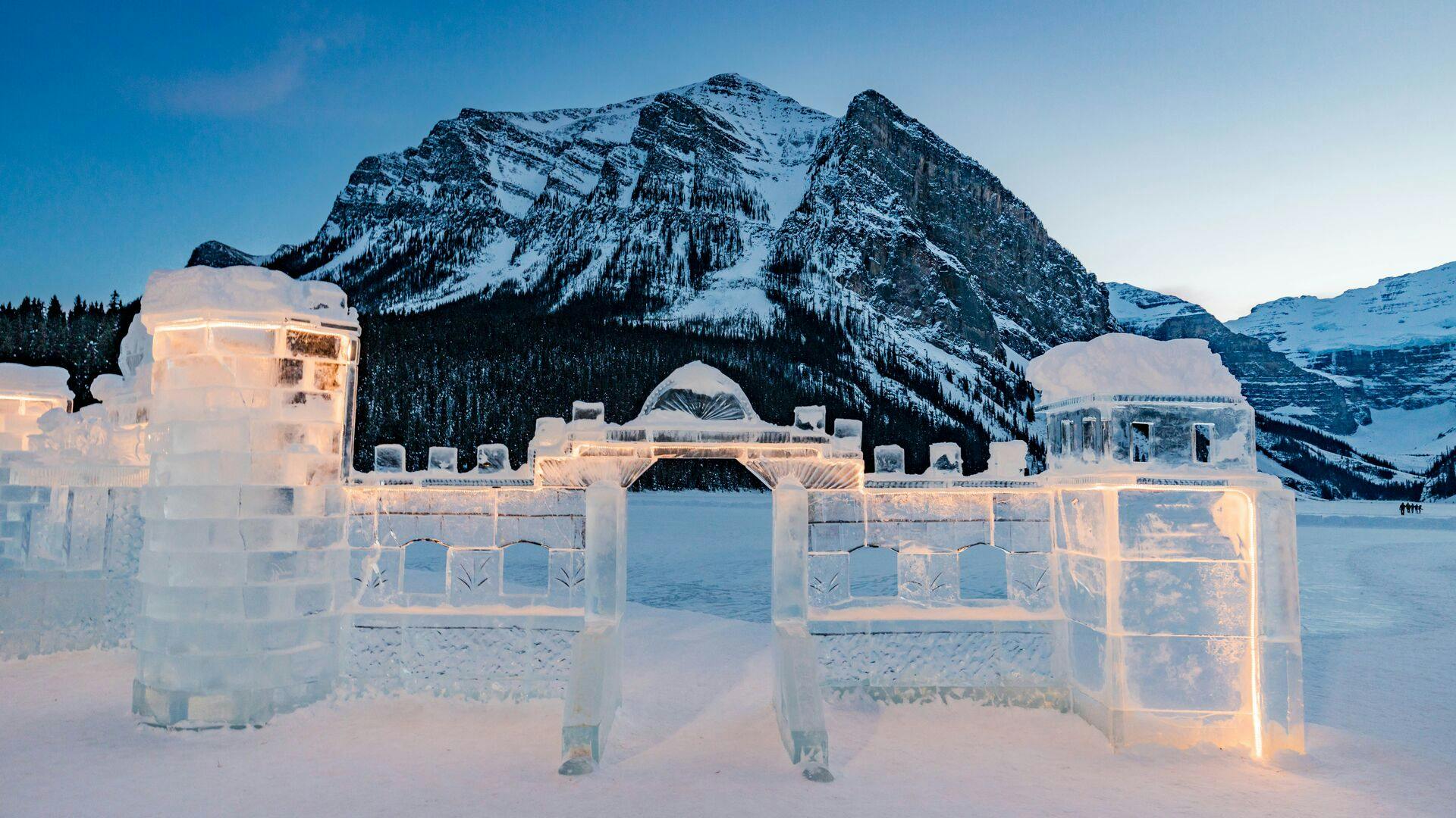 Ice castle sculpture framed by snowy Canadian Rockies