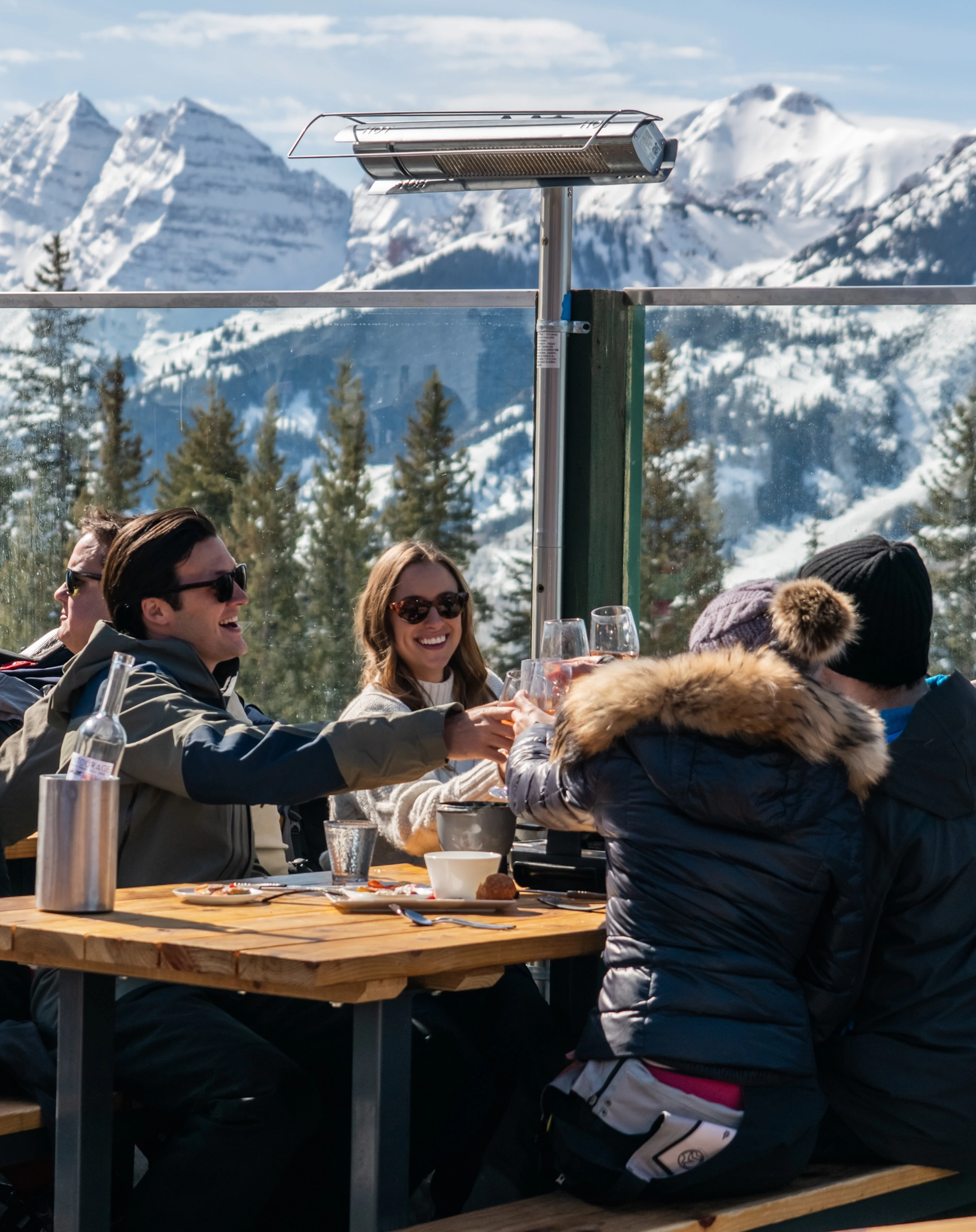 Friends toasting at a mountain table with scenic peaks behind them