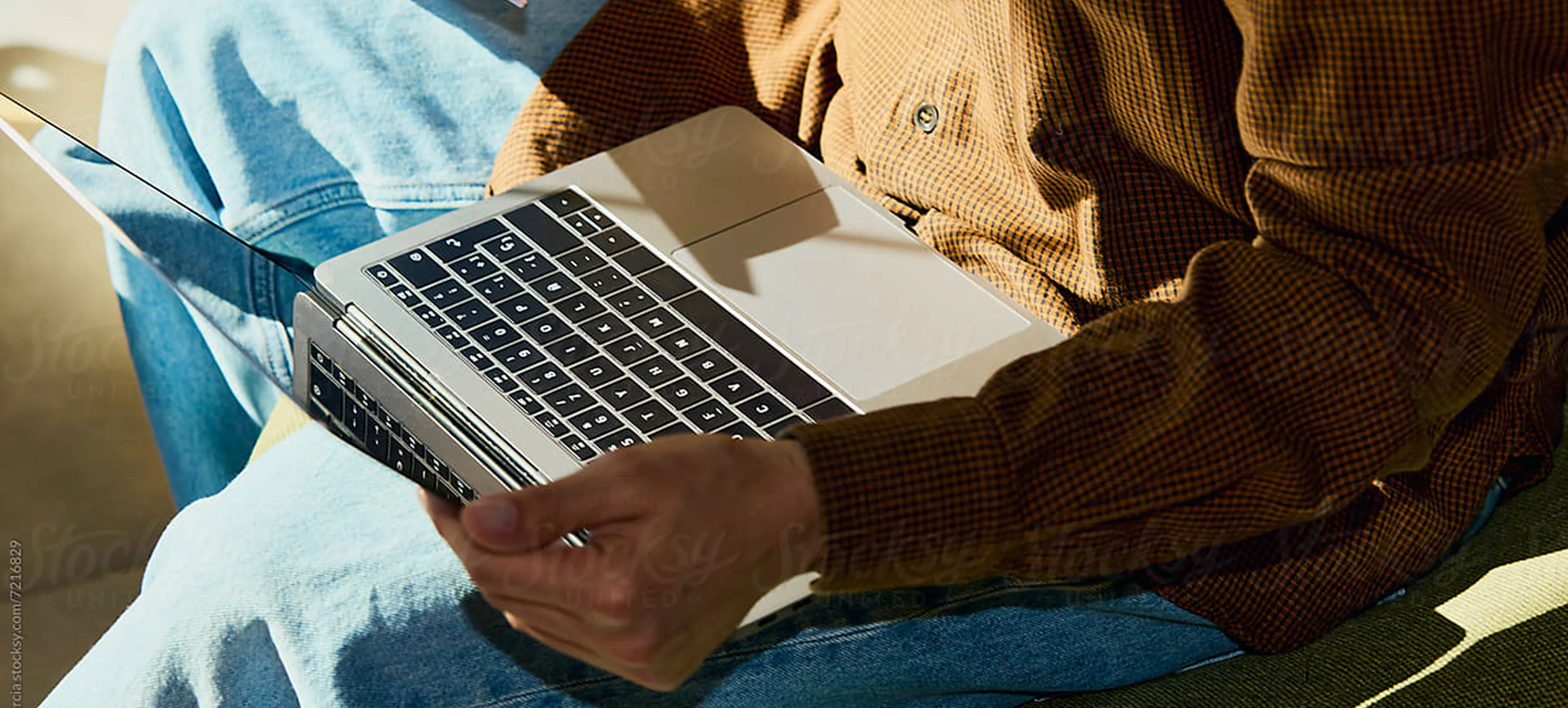 Collaborateur qui travaille sur un ordinateur portable posé sur ses genoux