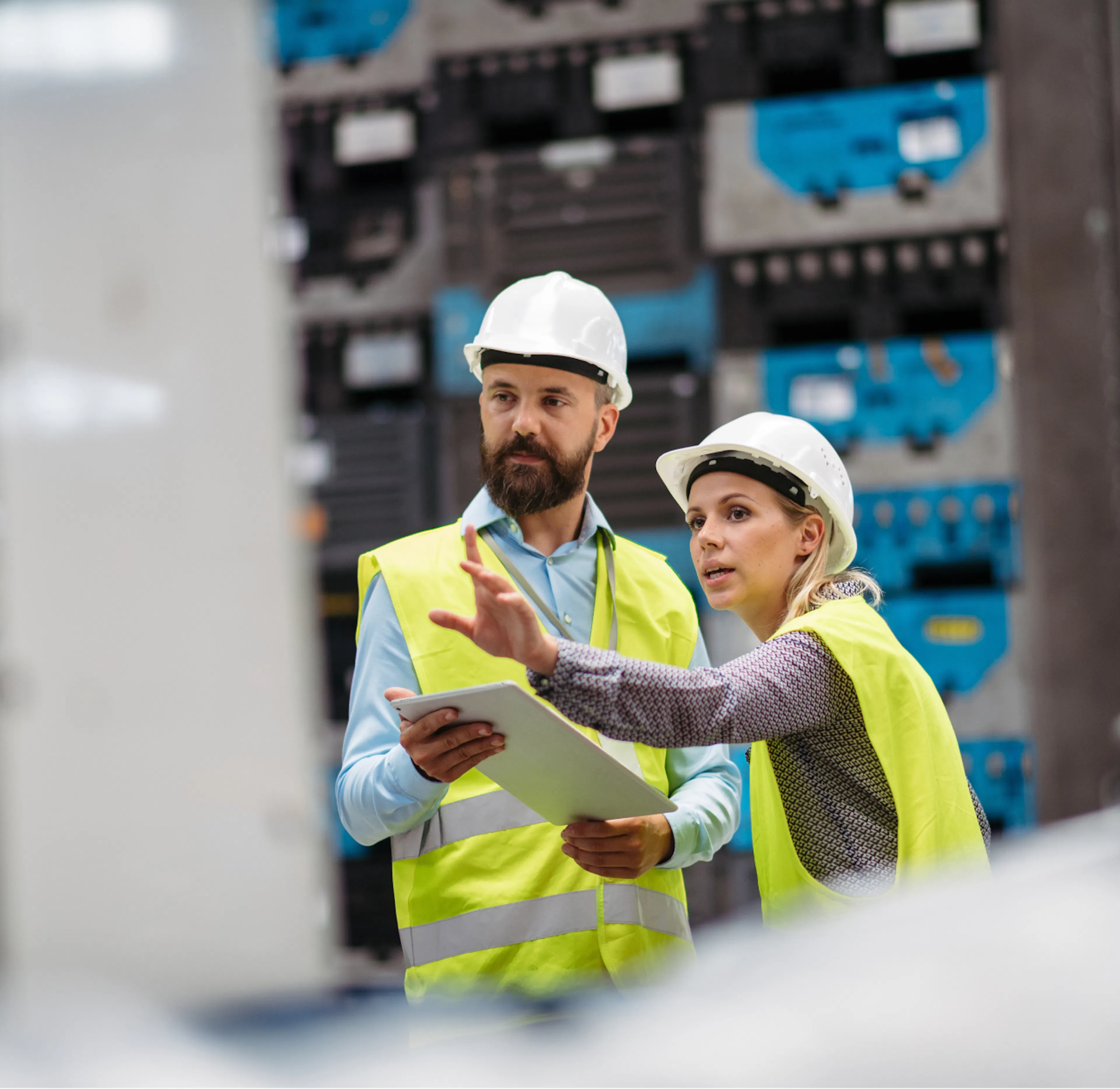 Deux techniciens en casque de chantier échangent devant une armoire électrique, tablette en main