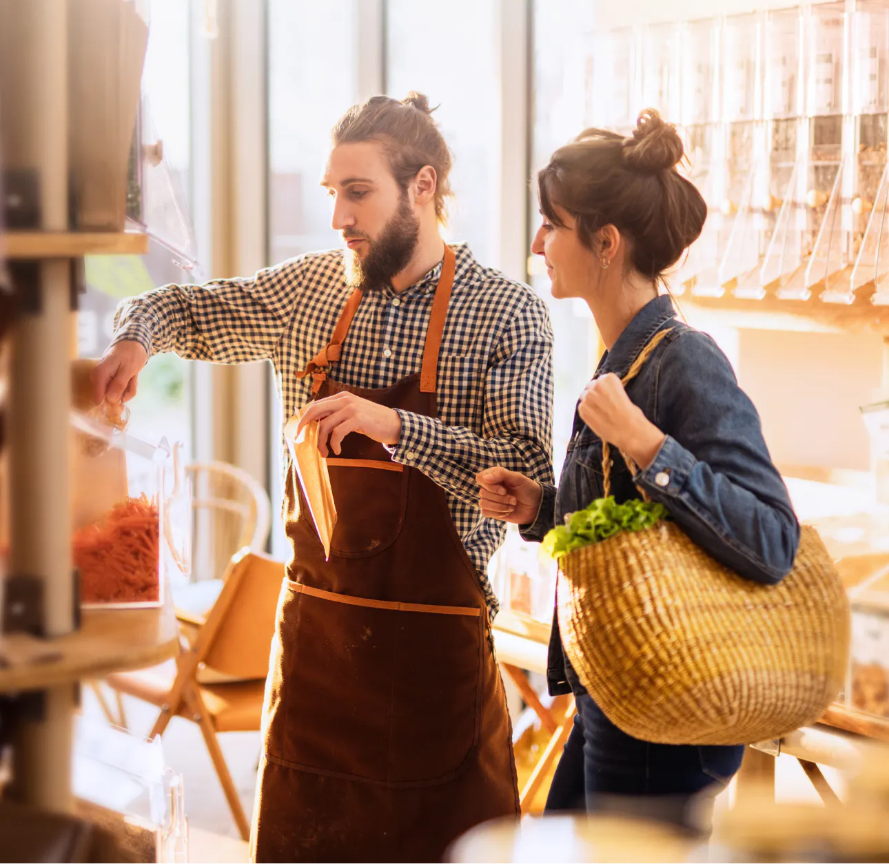Vendeur en tablier qui conseille une cliente en boutique