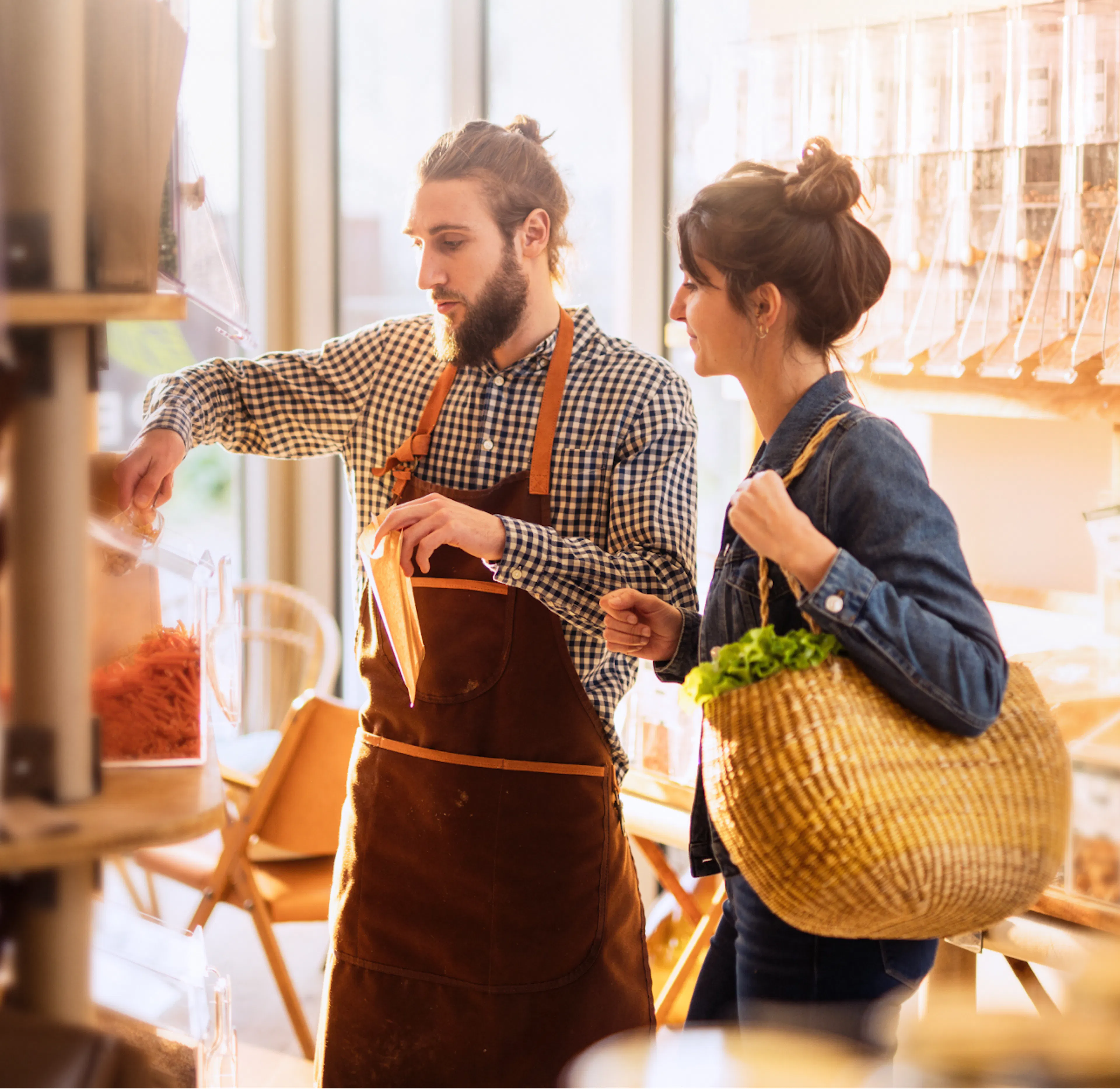 Vendeur en tablier qui conseille une cliente en boutique