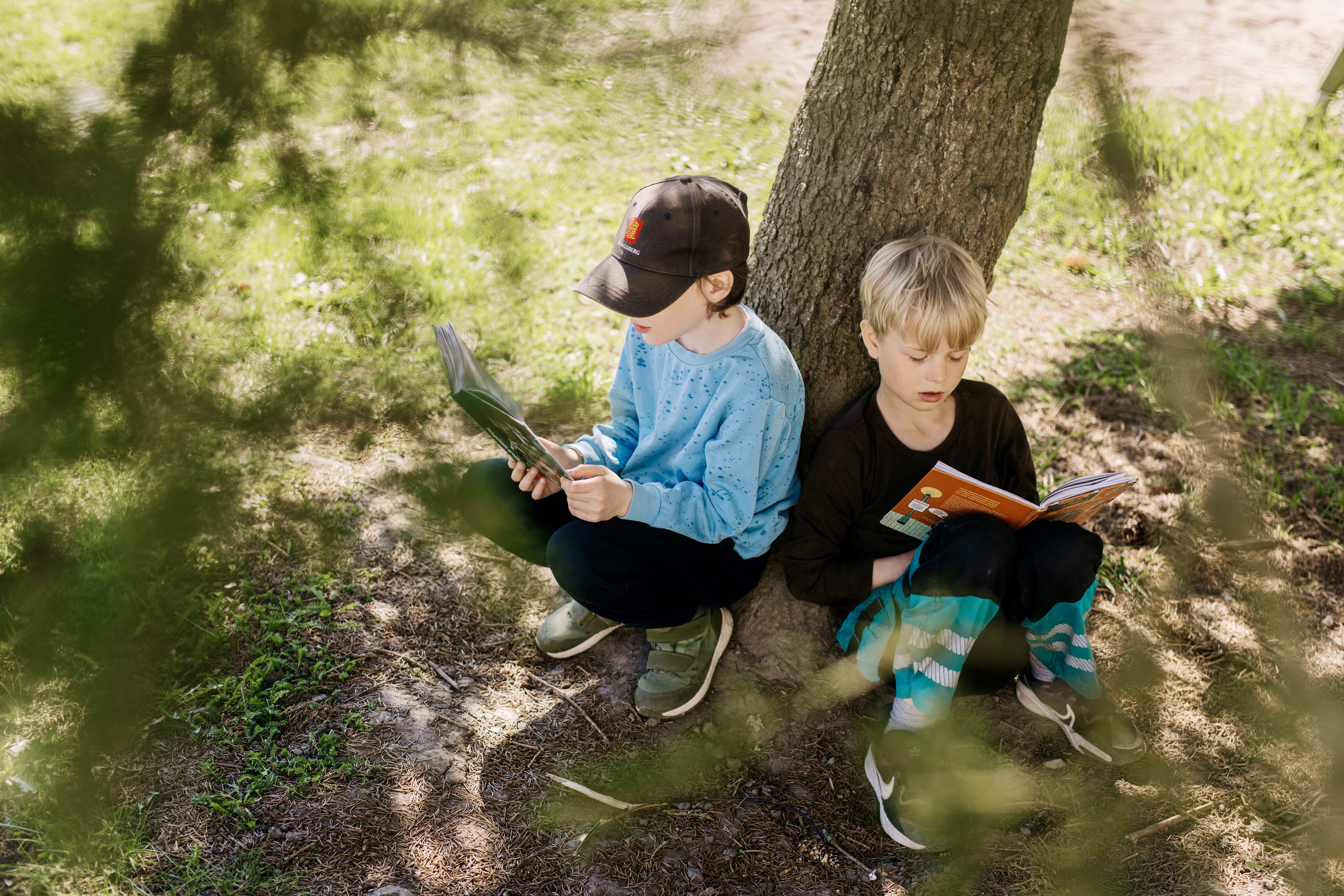 Alakoulun oppilaat lukevat puun alla kirjaa