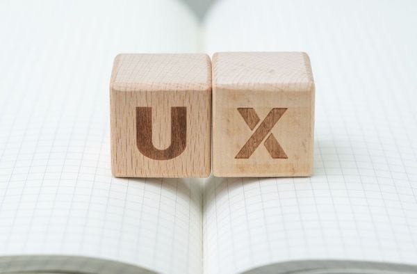 Wooden blocks with "UX" sitting on a notebook