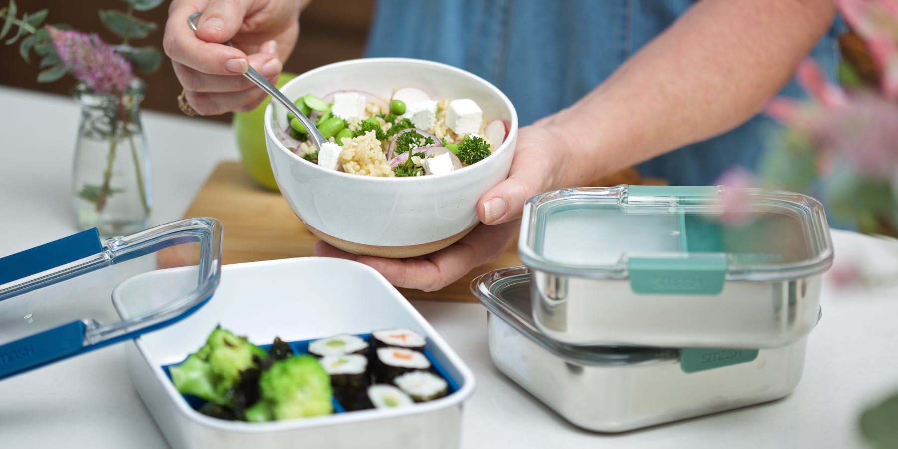 A person organising food into a stainless bento box