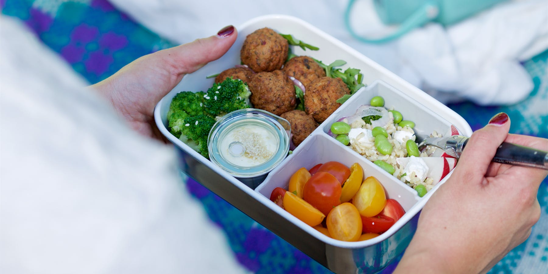A person enjoying food with a stainless steel bento
