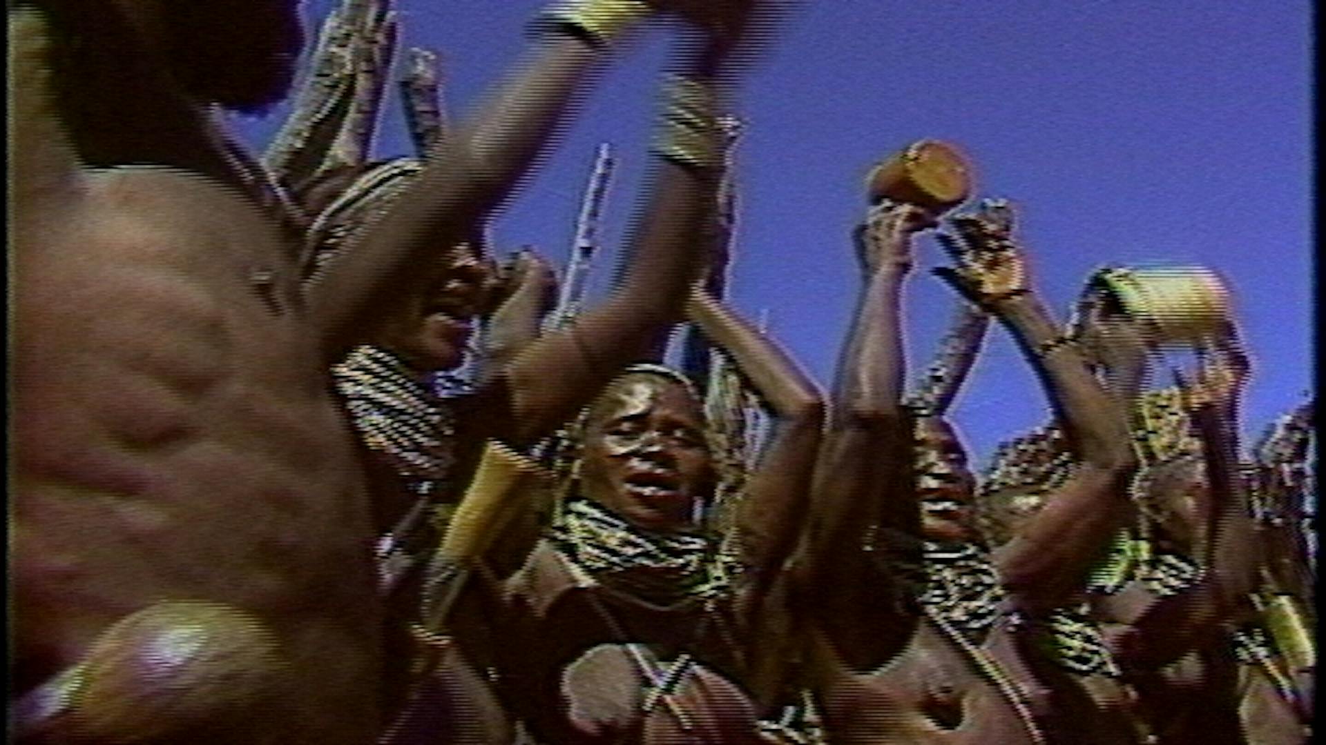 Um grupo de pessoas de comunidade Angolana dançam com adereços étnicos.