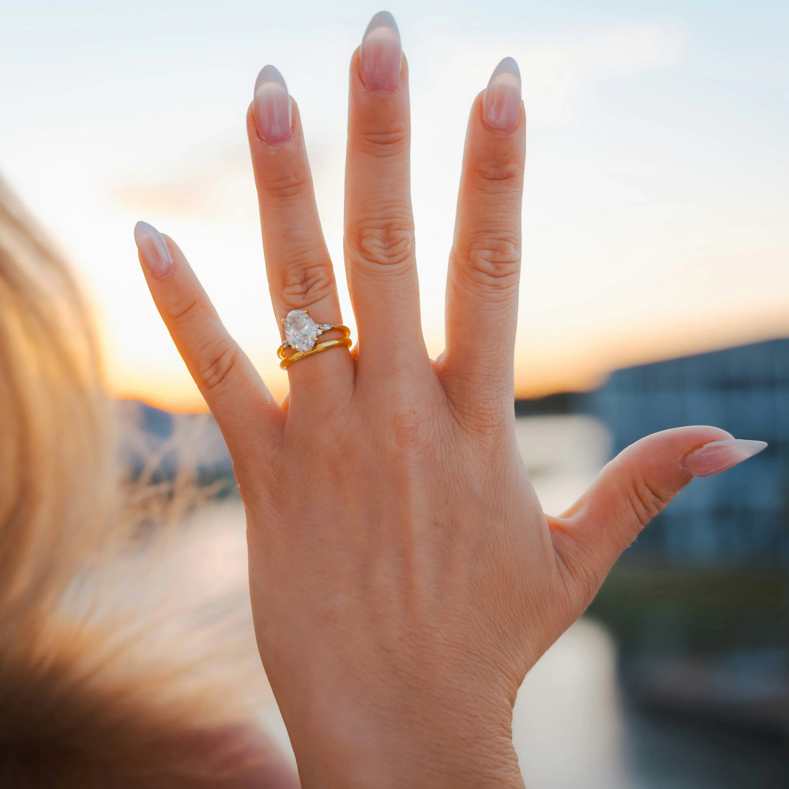 Celebrity inspired diamond engagement ring on a woman's hand at sunset