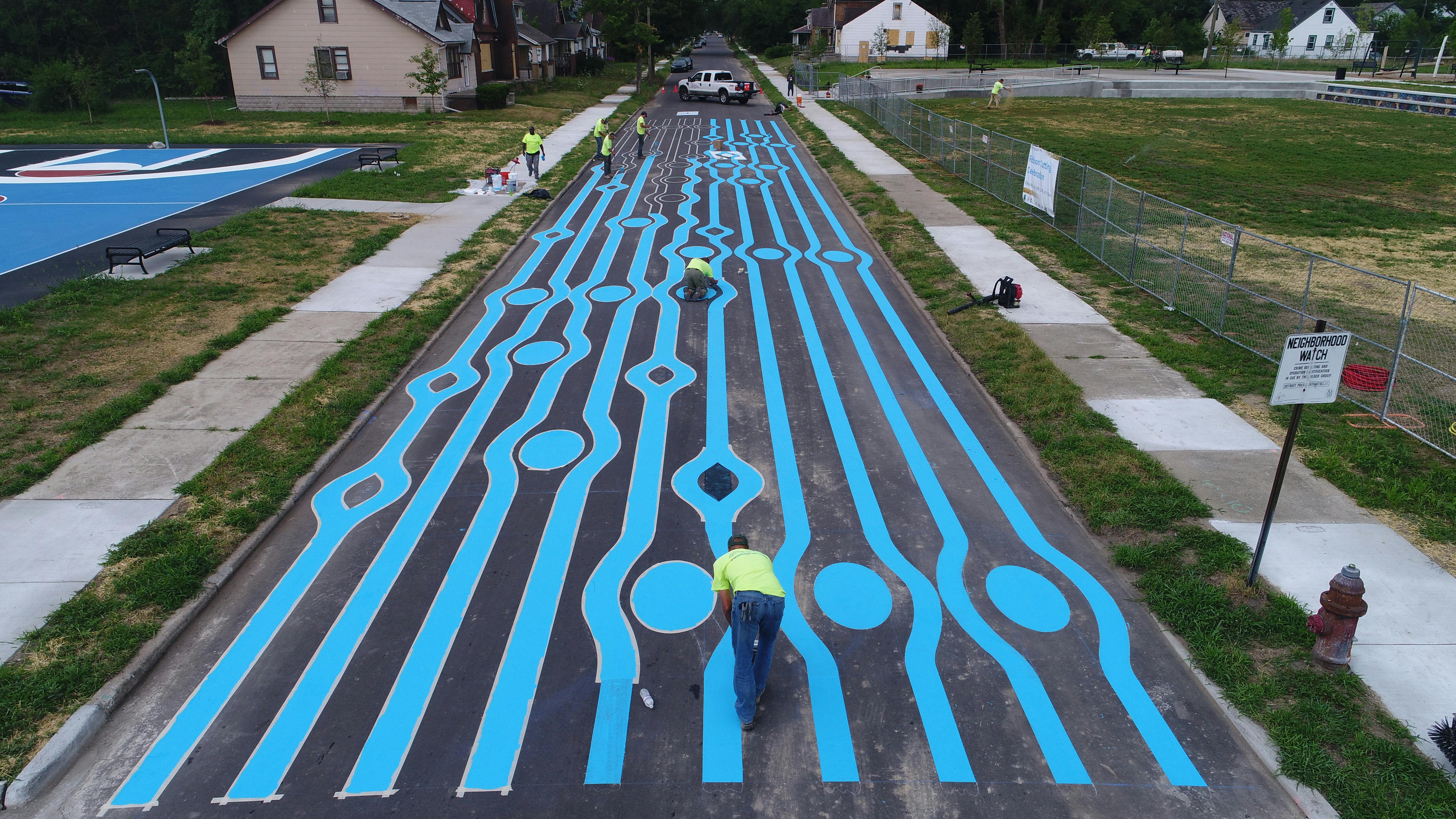 construction crew painting pattern of blue music notes on a street 