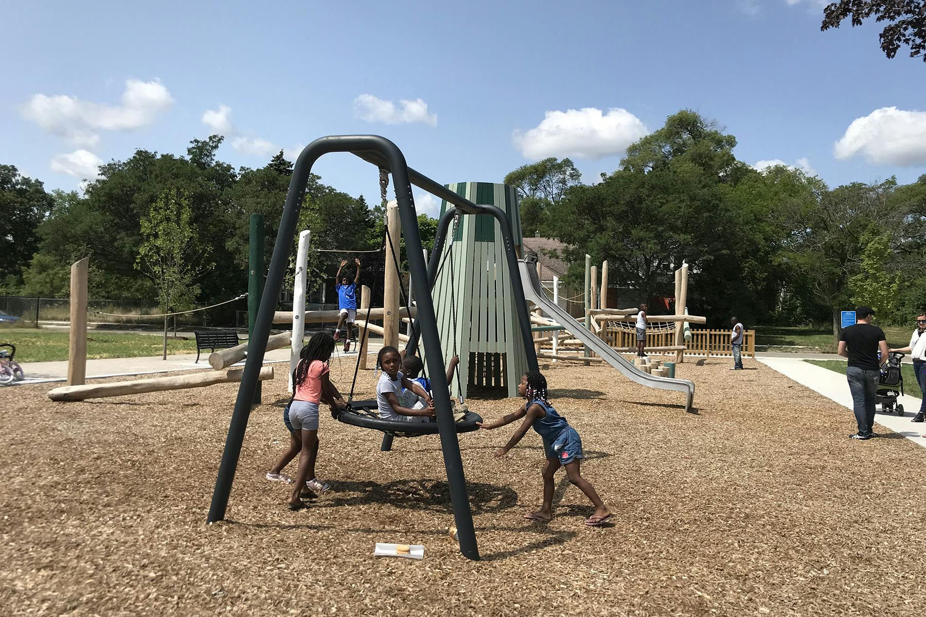Constructed photograph of the new playground with children playing on swing.