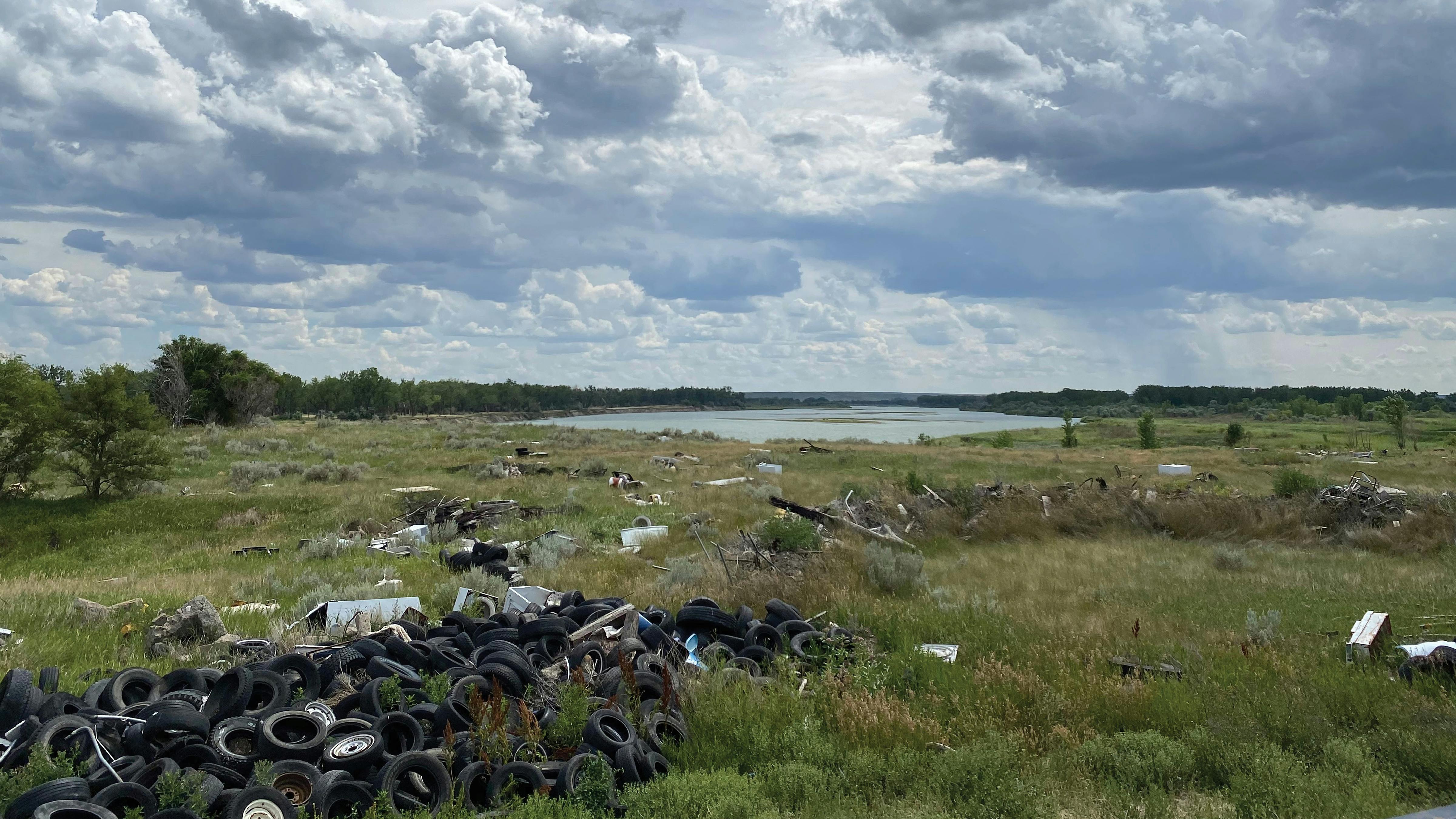 scene of grassy area along river with debris dumping in foreground