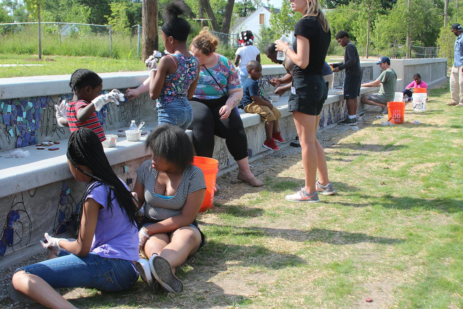 community members working together to put a mosaic on the wall in a park.