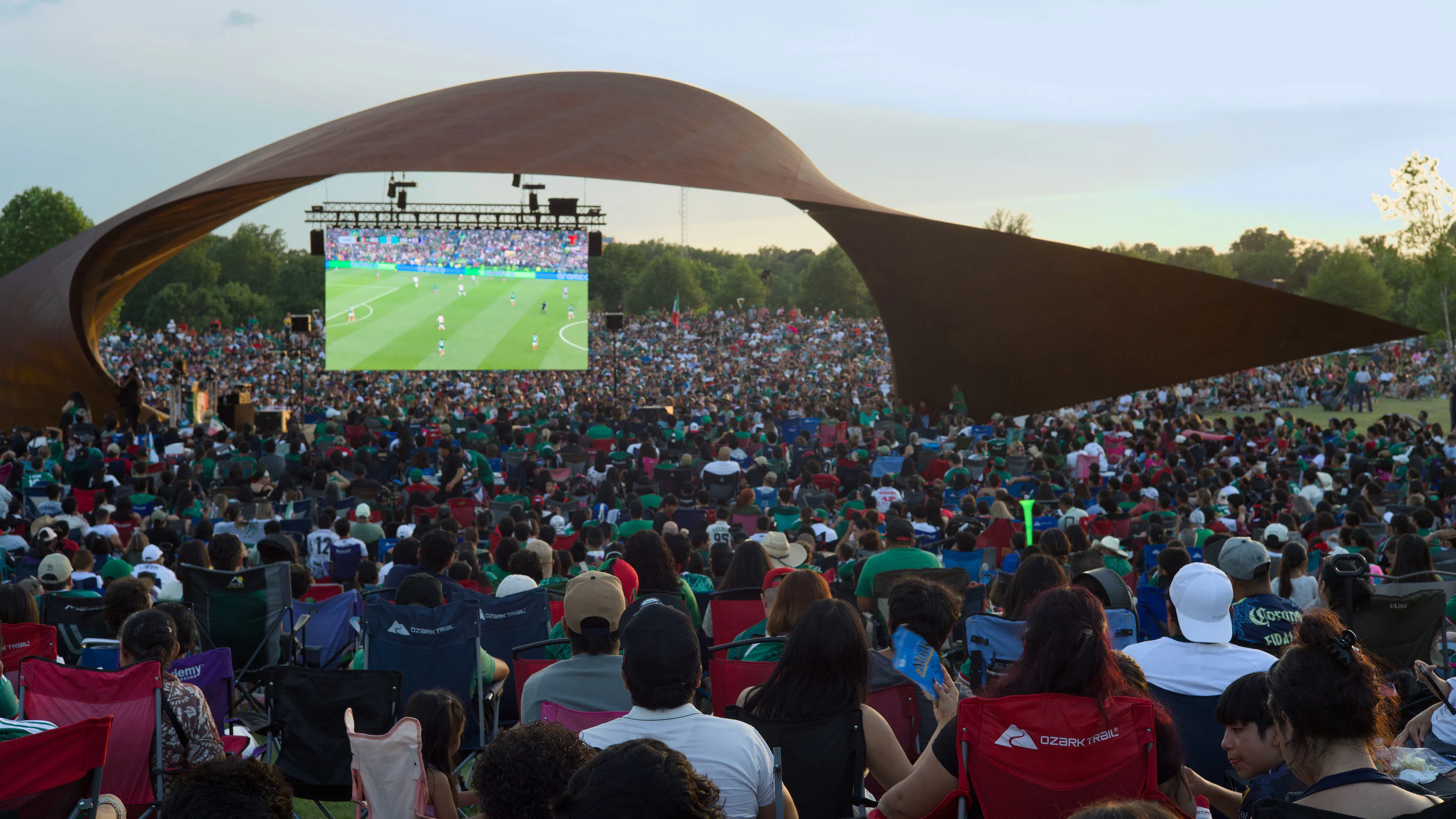 crowd watching soccer on big screen in park