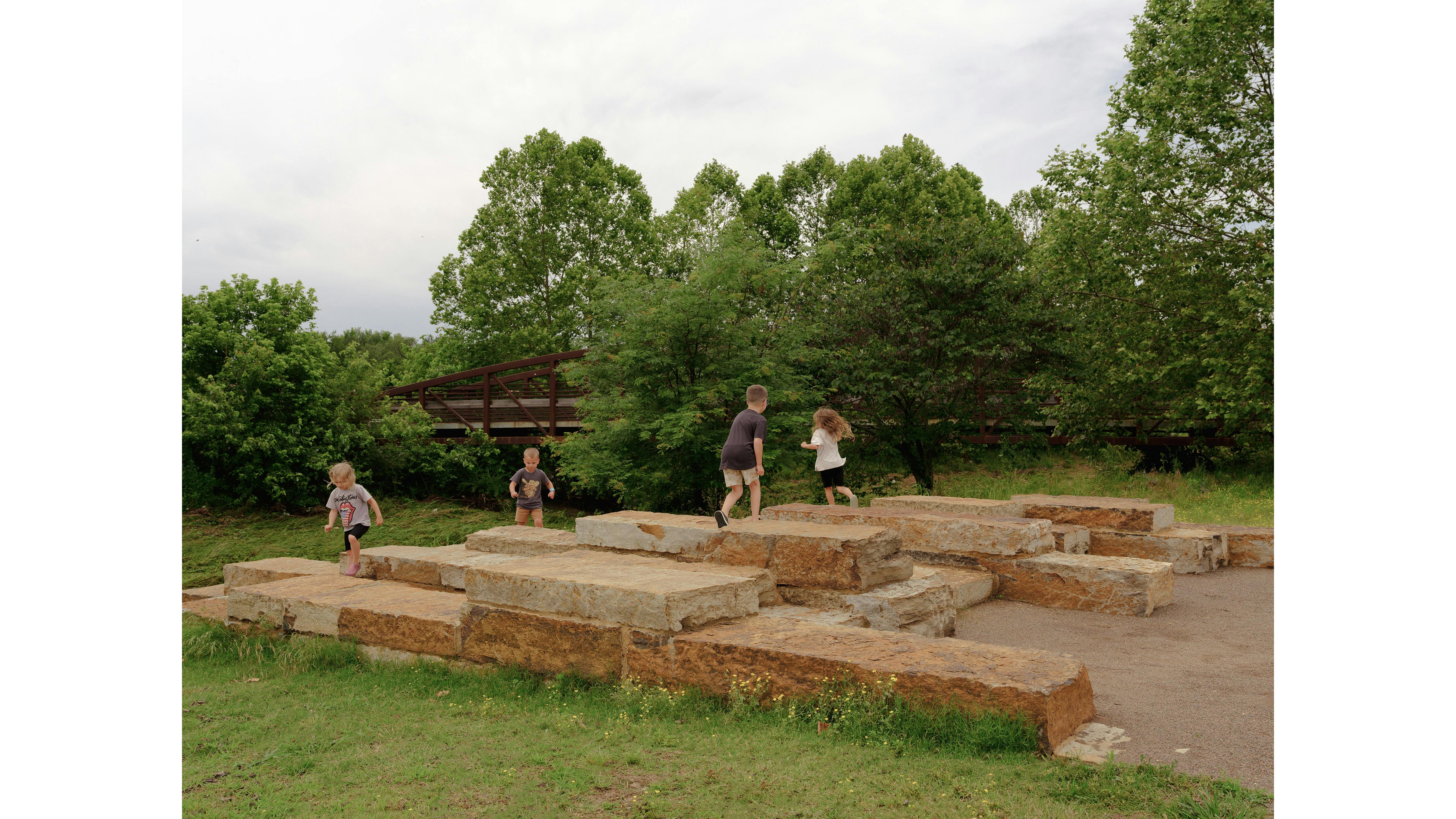 children playing on large stone steps by trees