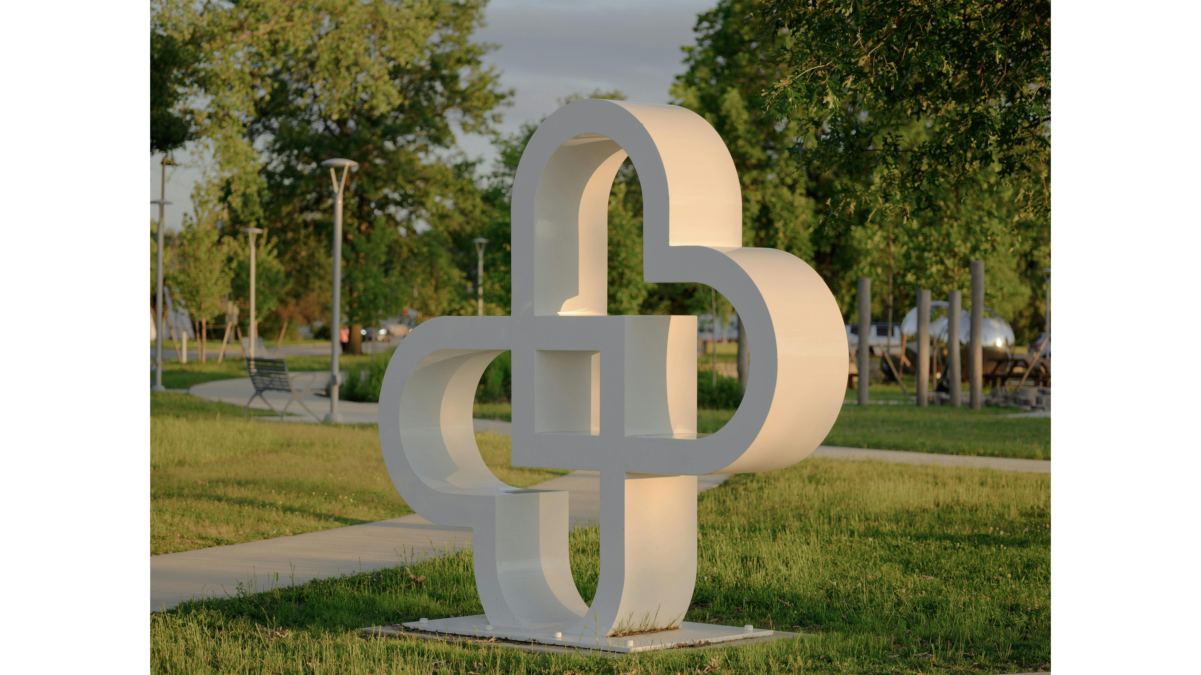 white sculpture in park shaped like two hearts crossing