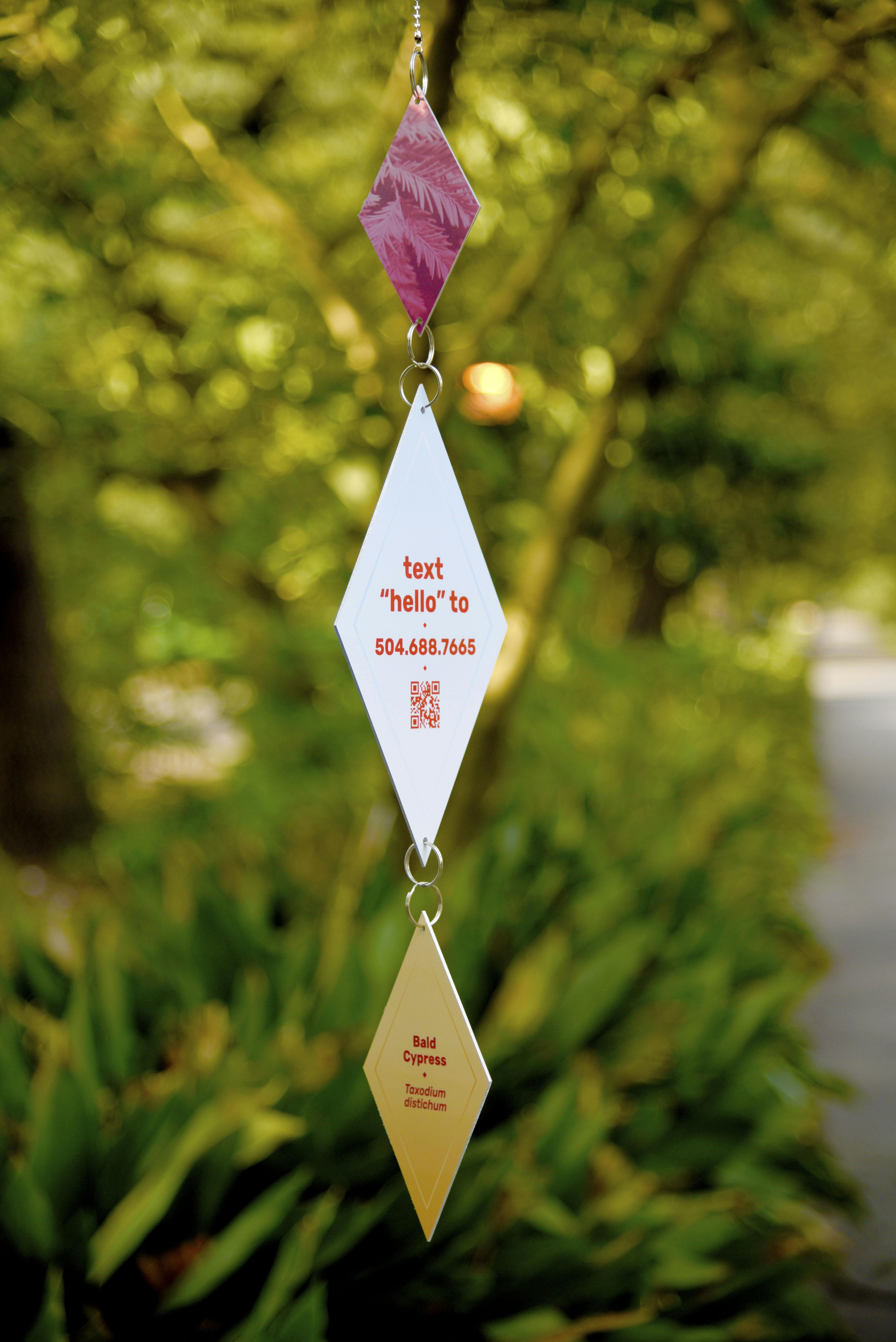 Three diamond shape Talk Tree To Me prototype with QR code and optional phone number hanging from tree.
