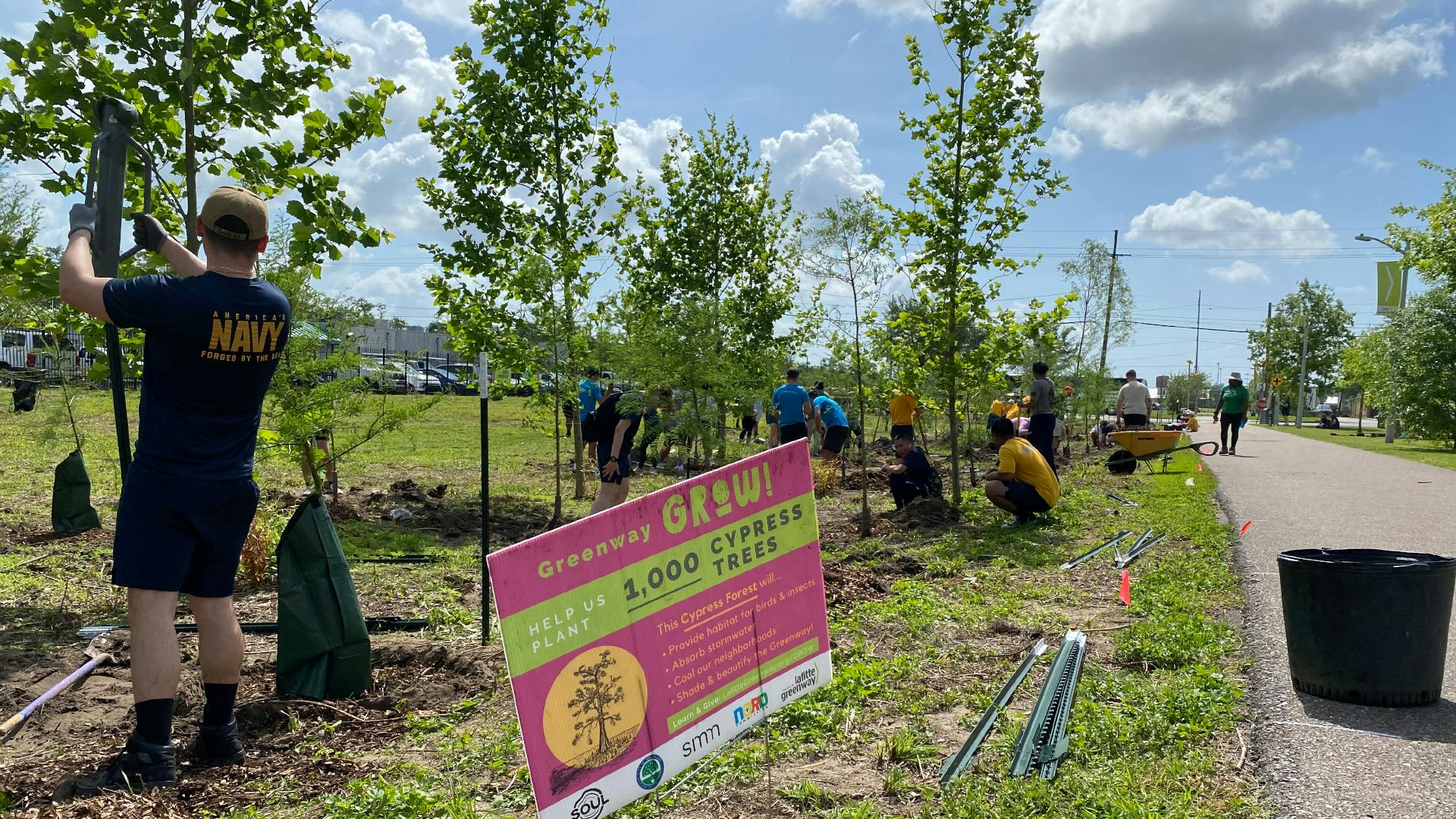 A group of volunteers planting native trees along the greenway.