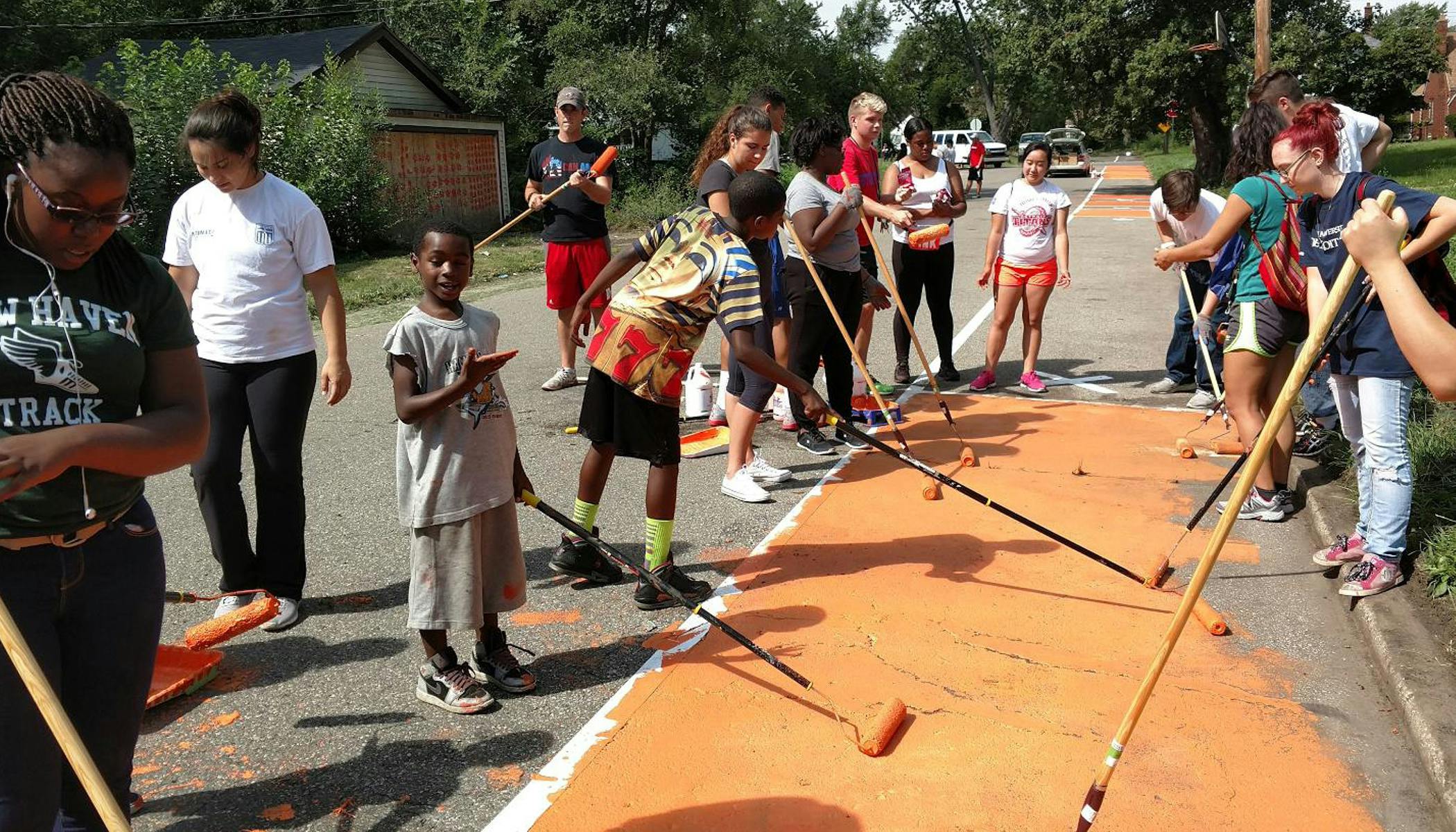 kids and teens work together to paint the proposed greenway in the neighborhood as part of the community engagement